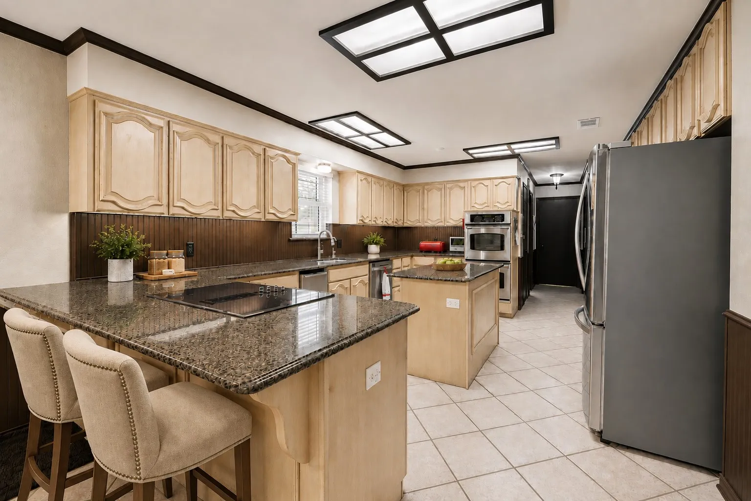 Kitchen featuring light-toned cabinetry, granite-finish countertops, stainless steel appliances, a center island, and tile flooring