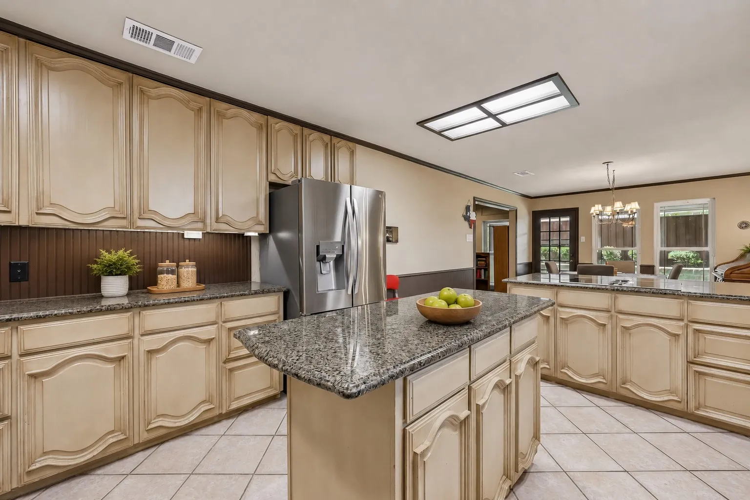 Kitchen featuring light-toned cabinetry, granite-finish countertops, stainless steel refrigerator, and tiled flooring