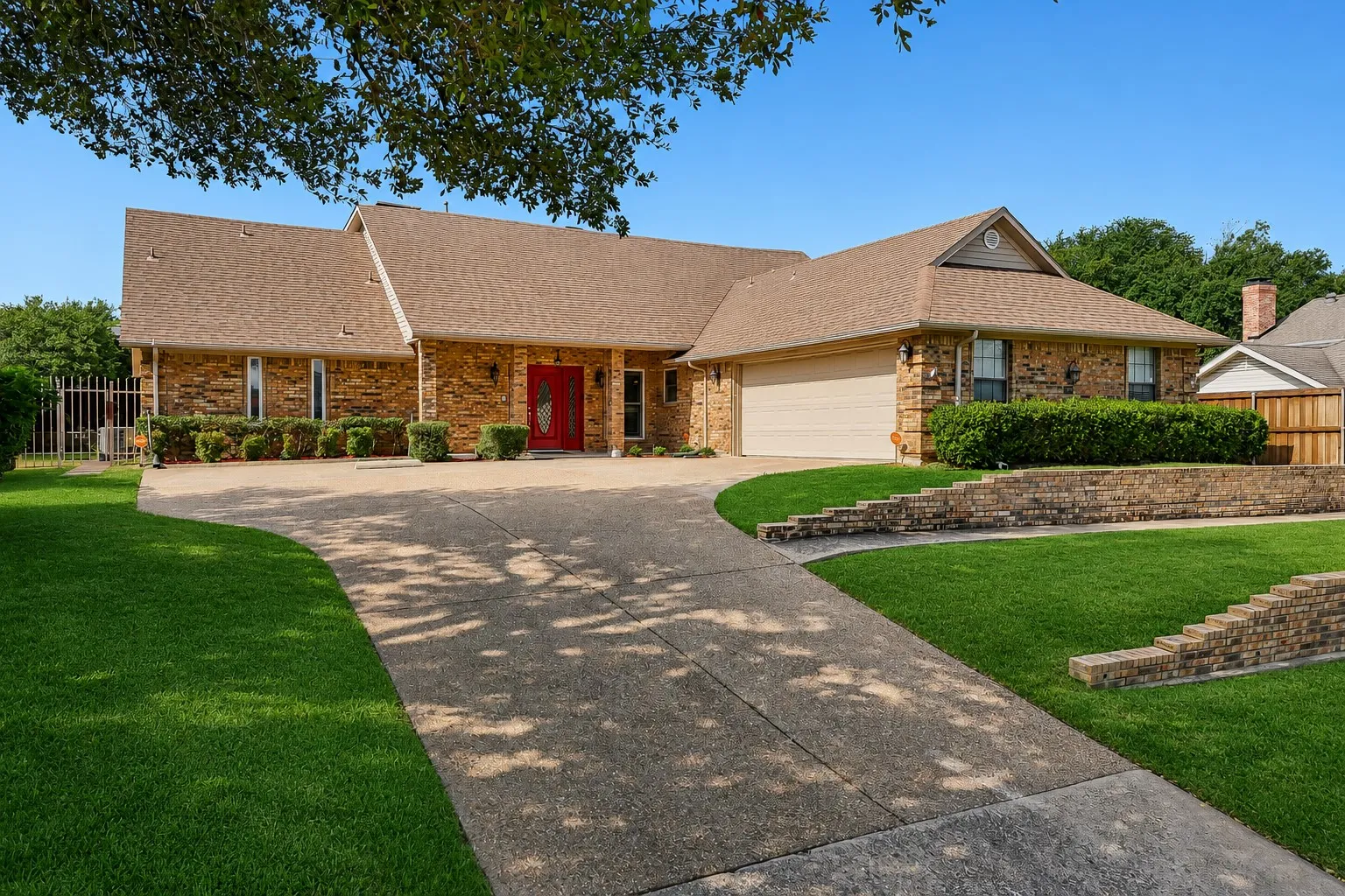 Brick-clad exterior with a red double-door entry, a two-car garage, and a concrete driveway