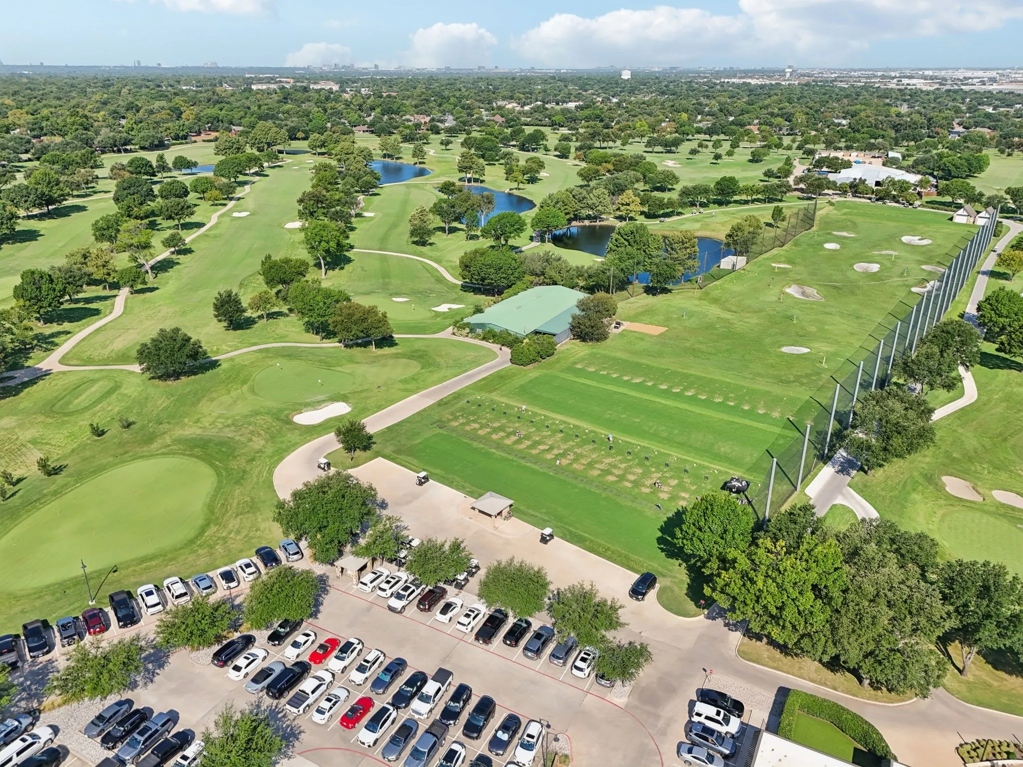Expansive golf course featuring a driving range, multiple greens, sand traps, and water features