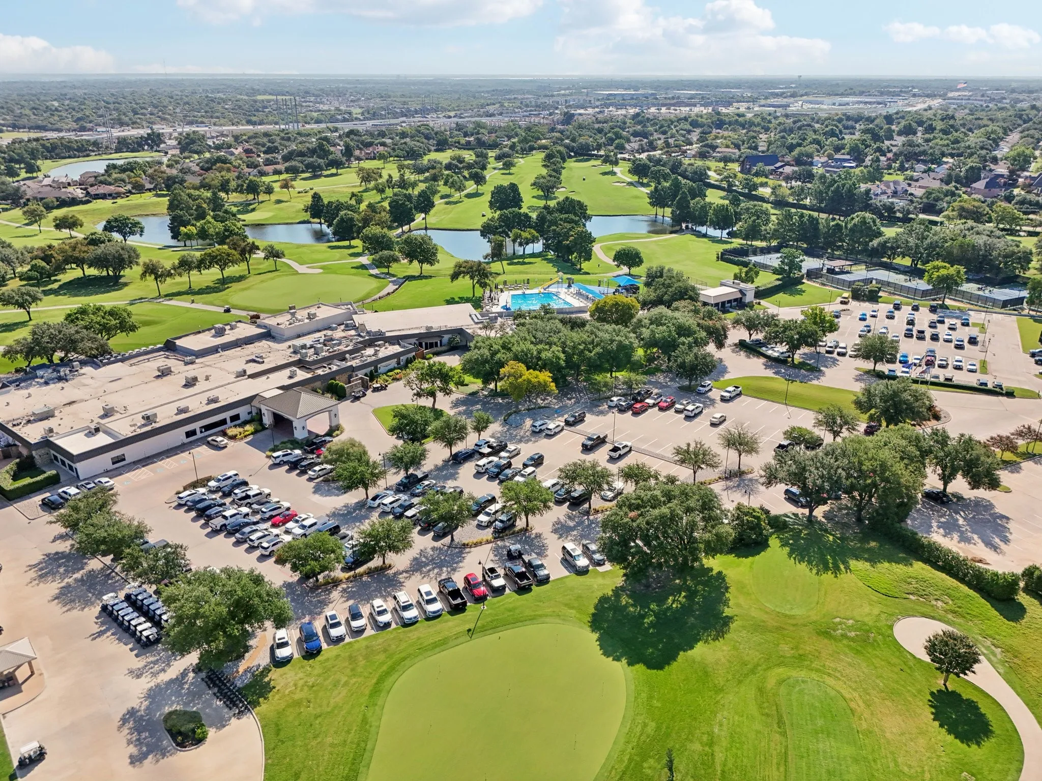 Aerial perspective showcasing a sprawling golf course with multiple water features, manicured greens, and mature trees