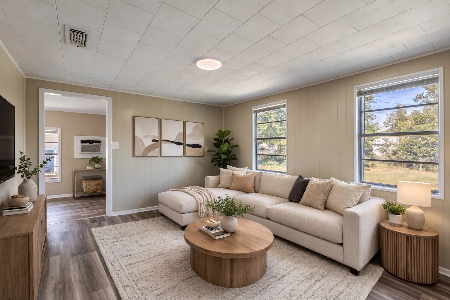 Living area featuring wood-finish flooring, a neutral color palette, multiple windows, and a ceiling-mounted light fixtureAi Staged.