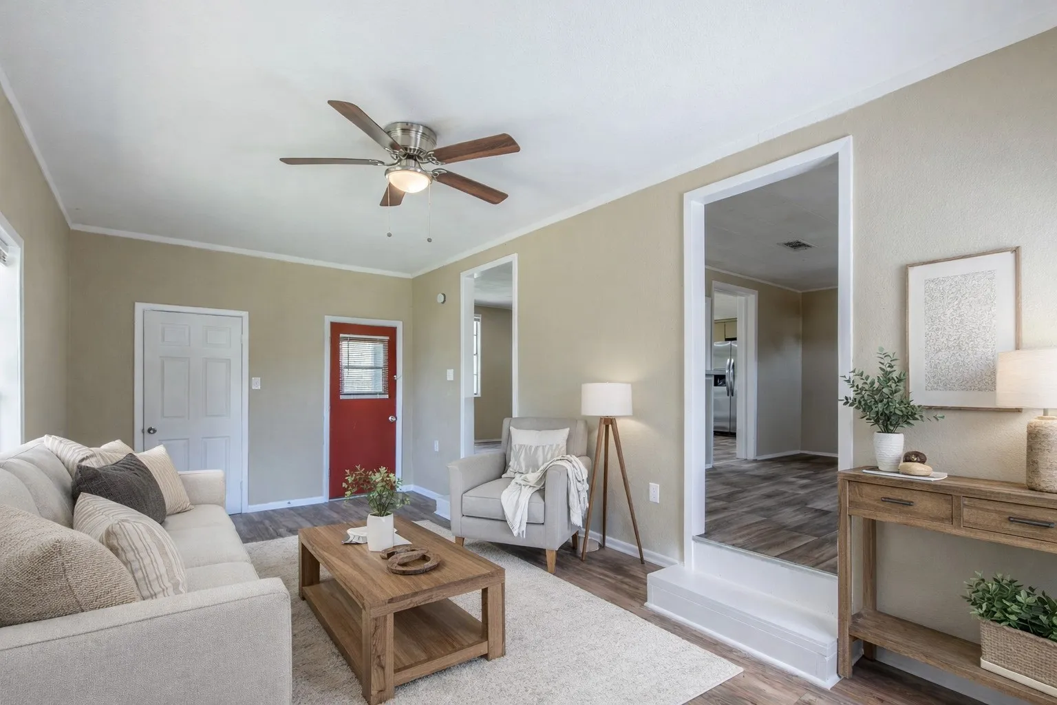 Living area featuring wood-finish flooring, a ceiling fan with integrated lighting, and a white paneled doorAi Staged.