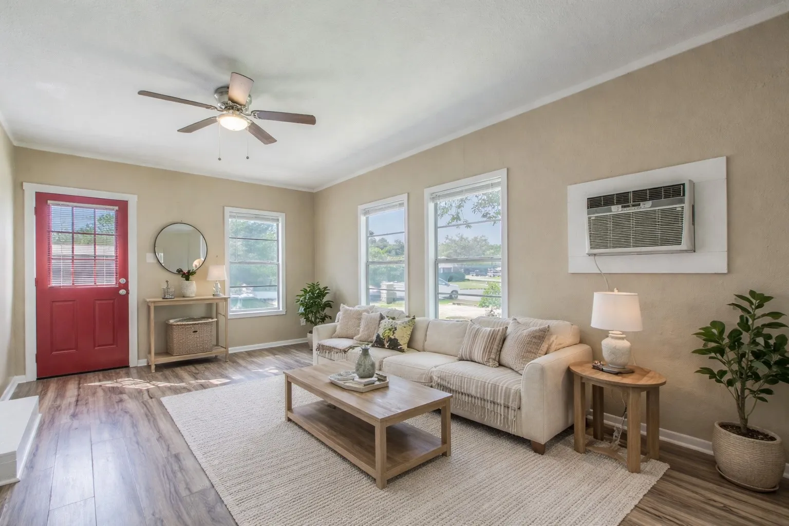 Living area featuring wood-finish flooring, a ceiling fan, and multiple windowsAi Staged.