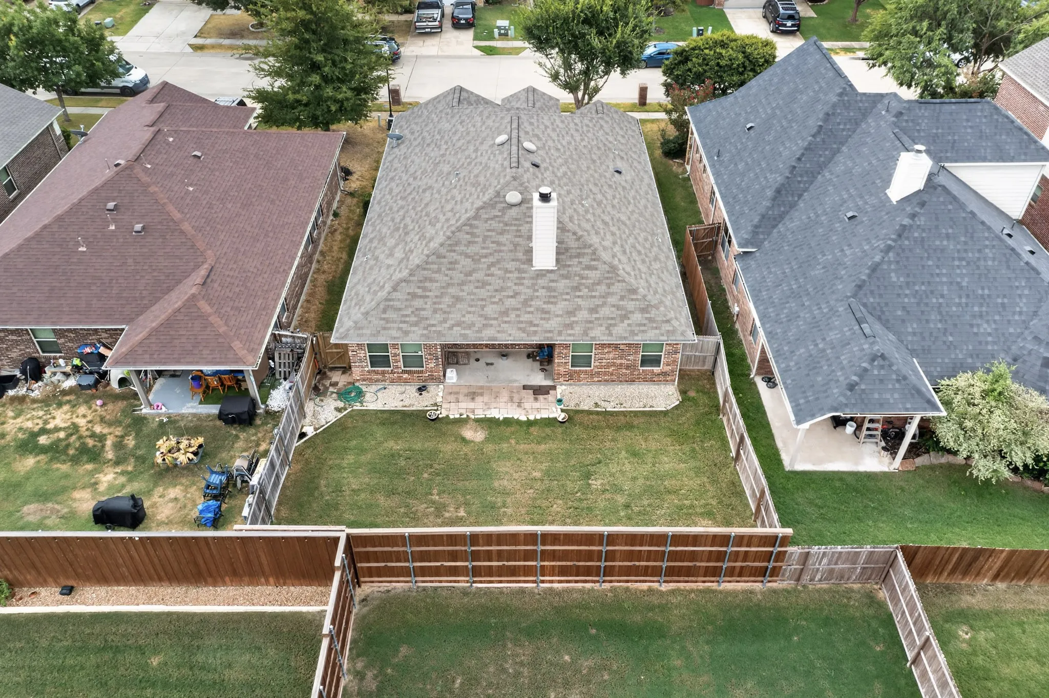 Fenced backyard with a covered patio, brick exterior, and a shingled roof