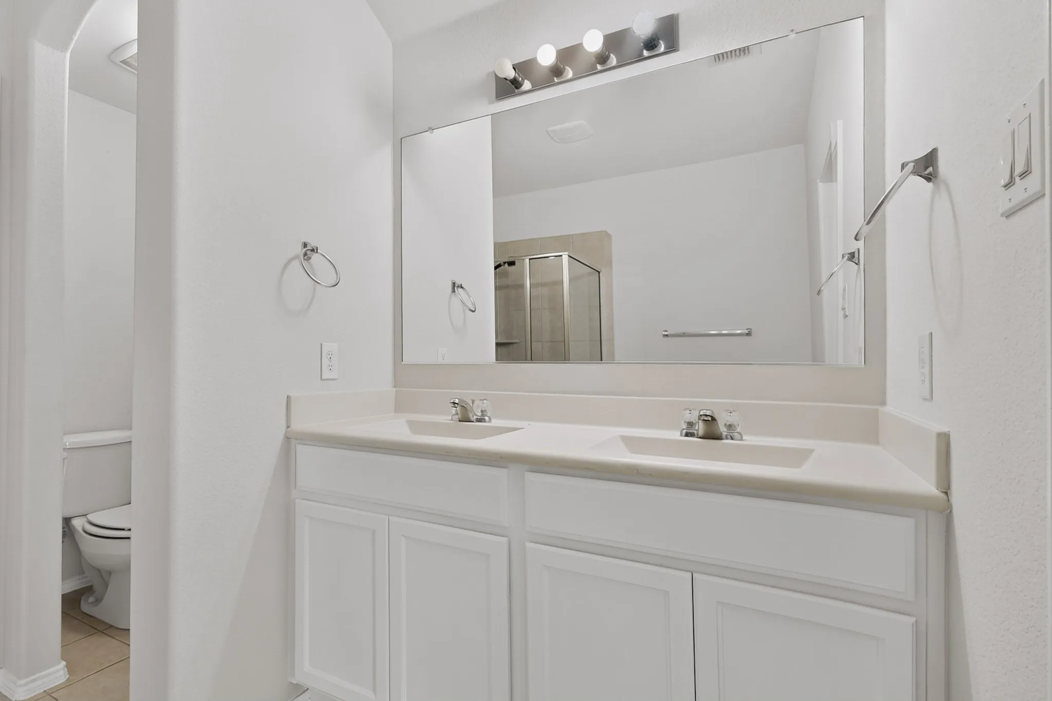 Dual vanity with undermount sinks, light-toned countertop, and white cabinetry