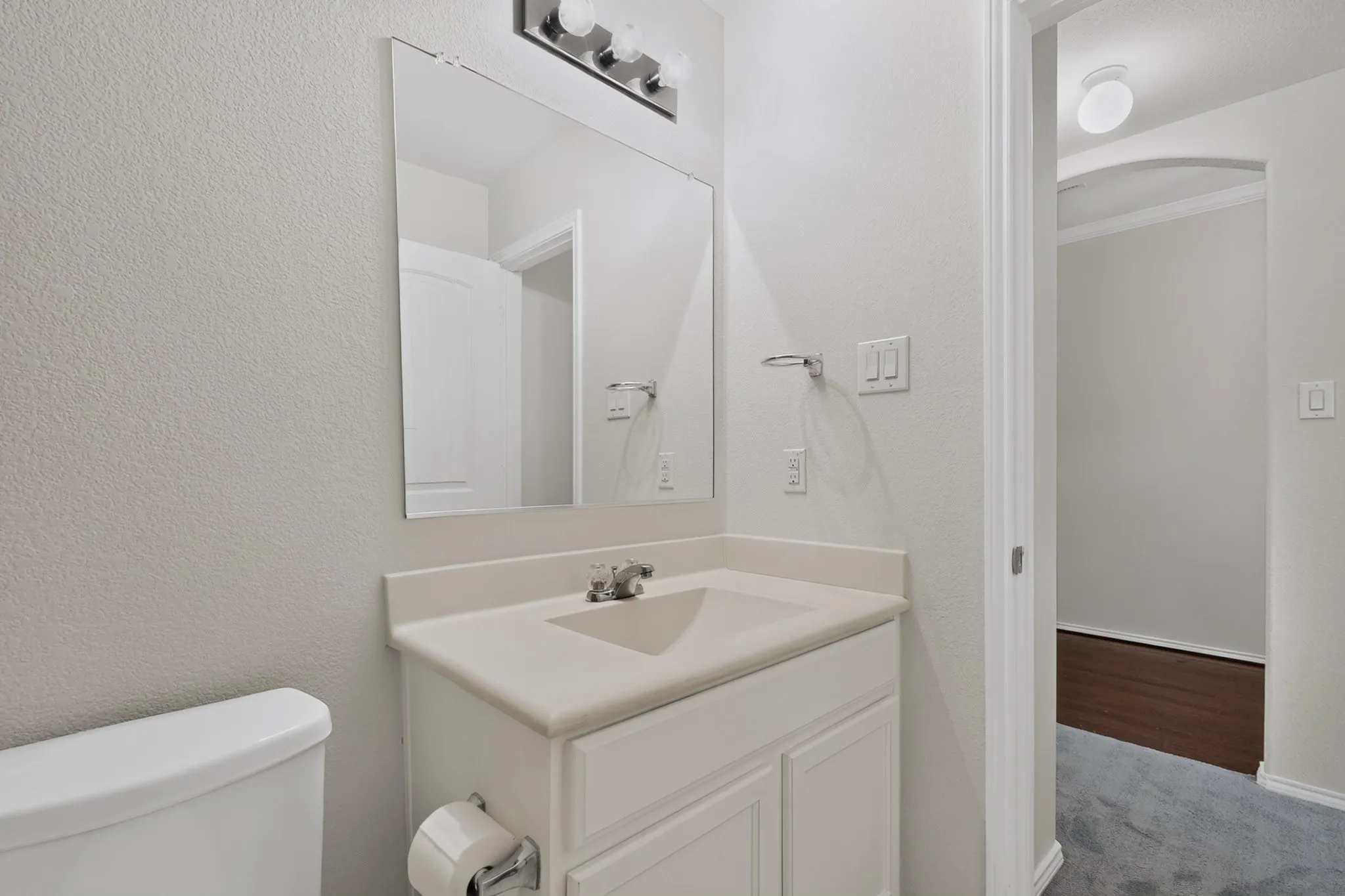 White vanity with a built-in sink, chrome faucet, and overhead light fixture