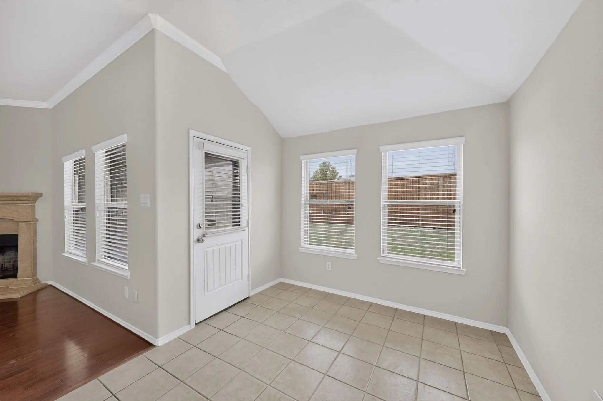 Vaulted ceilings, a rear exterior door, and multiple windows with blinds