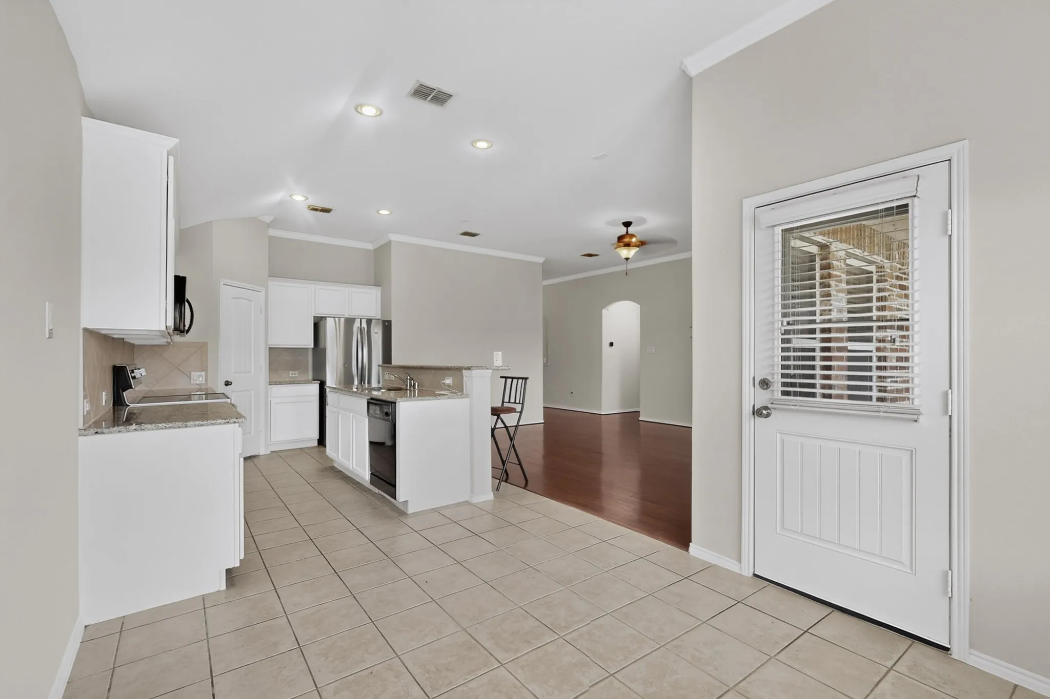 Kitchen featuring tile flooring, white cabinetry, integrated stainless steel appliances, and a pass-through counter