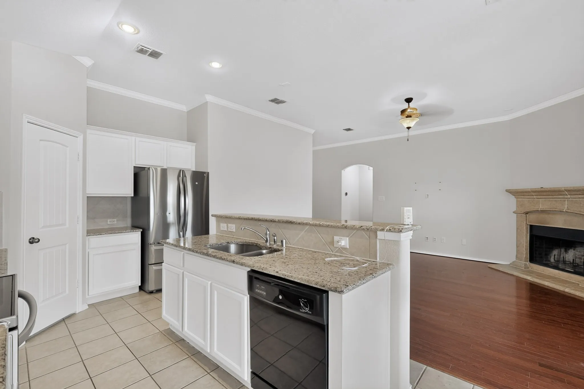 Kitchen featuring white cabinetry, stainless steel refrigerator, tile flooring, and a breakfast bar with stone-look countertop