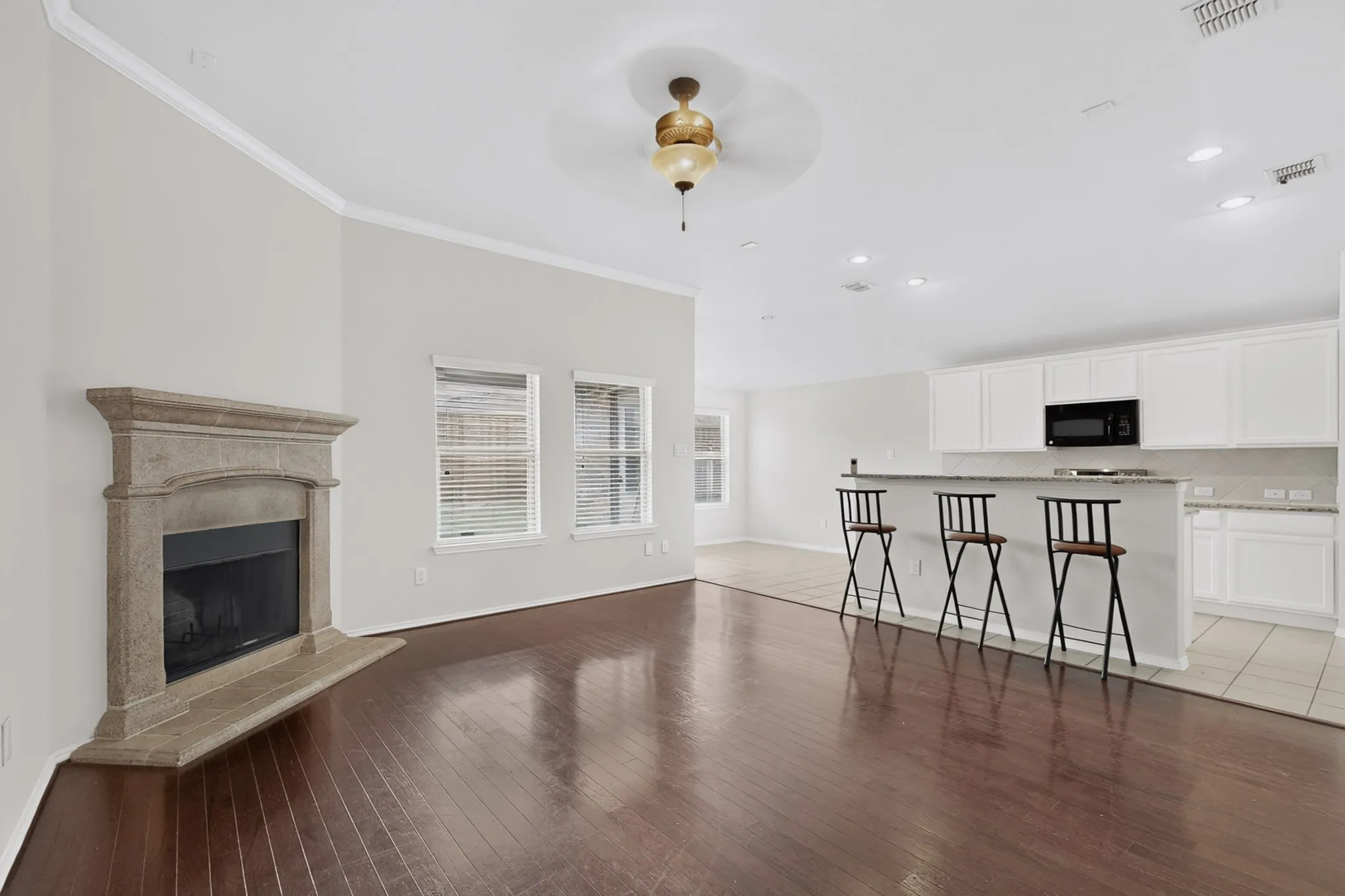Hardwood-style flooring throughout, corner fireplace, recessed lighting, crown molding, and a kitchen featuring white cabinetry