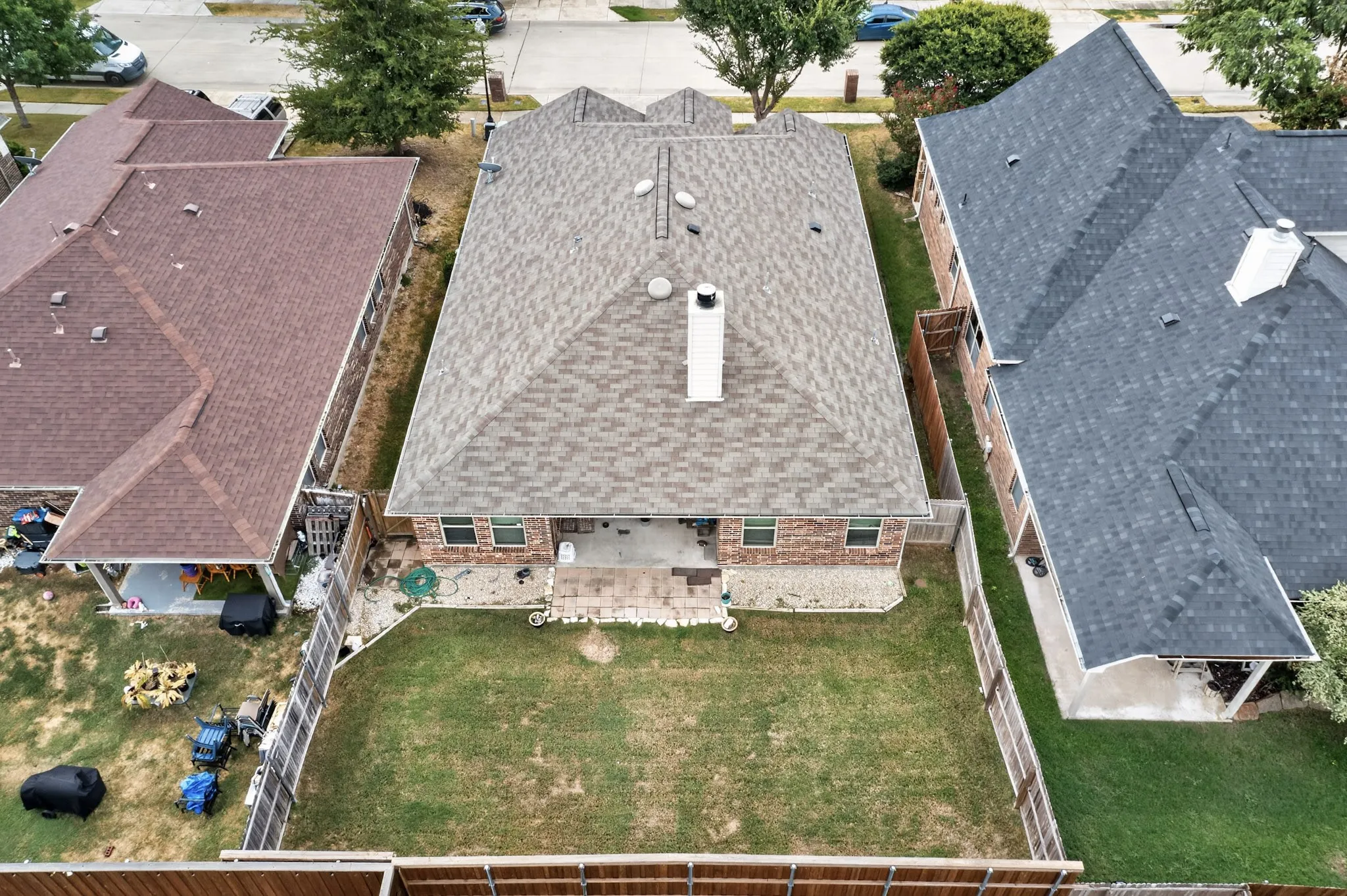 Expansive backyard featuring a manicured lawn, paved patio, and perimeter fencing