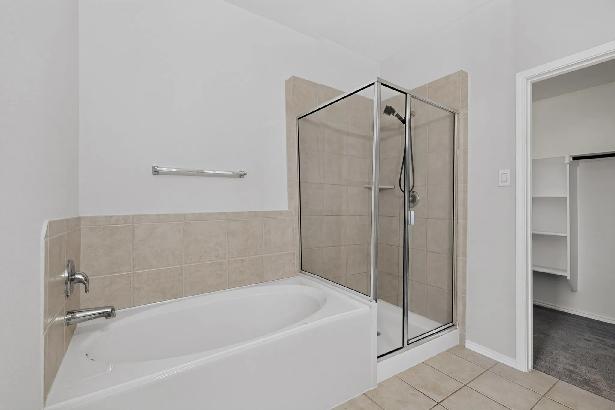 Built-in bathtub with chrome fixtures, glass-enclosed shower with tiled surround, and ceramic tile flooring