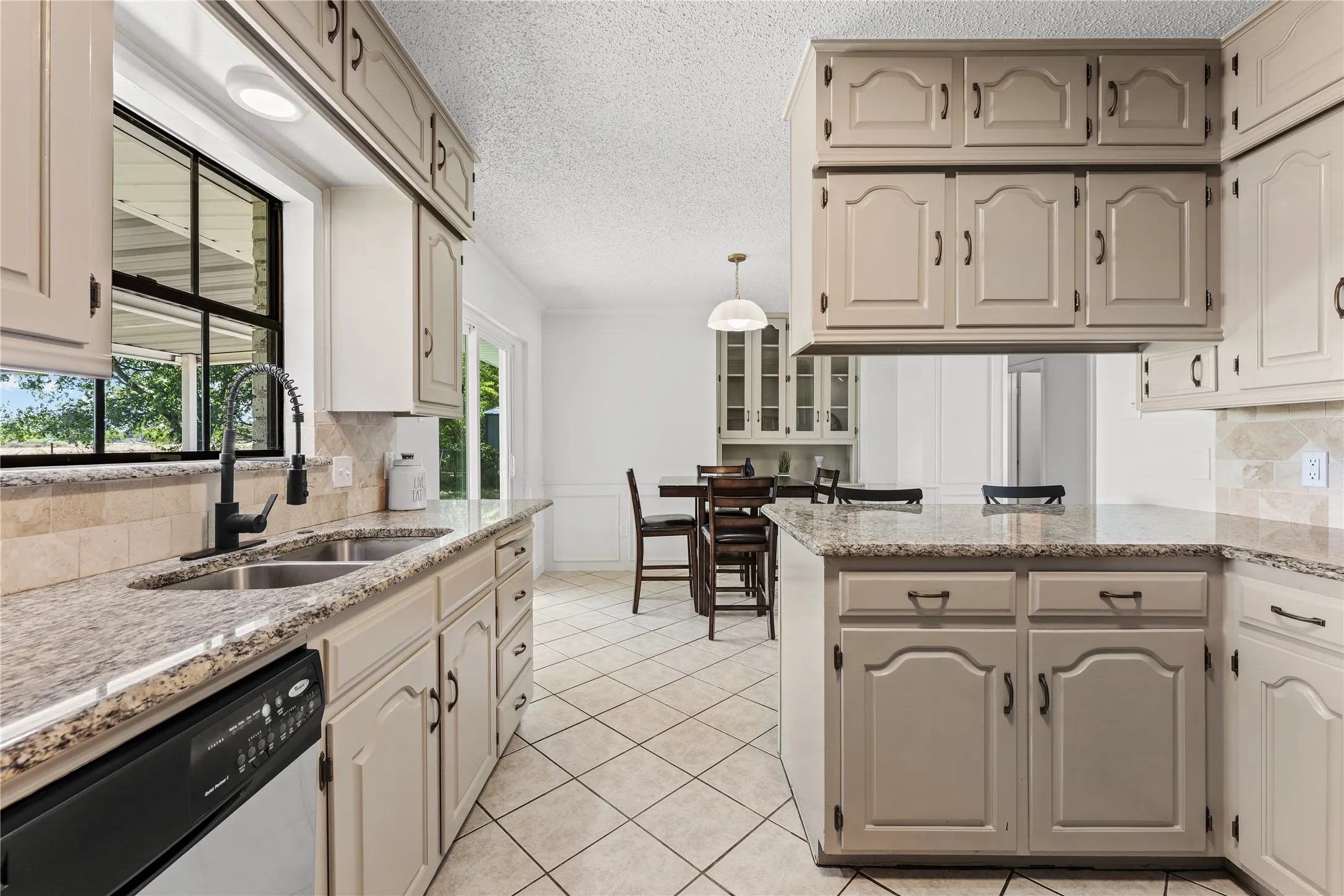 Kitchen featuring light-toned cabinetry, a double basin sink with a matte black faucet, and patterned tile flooring