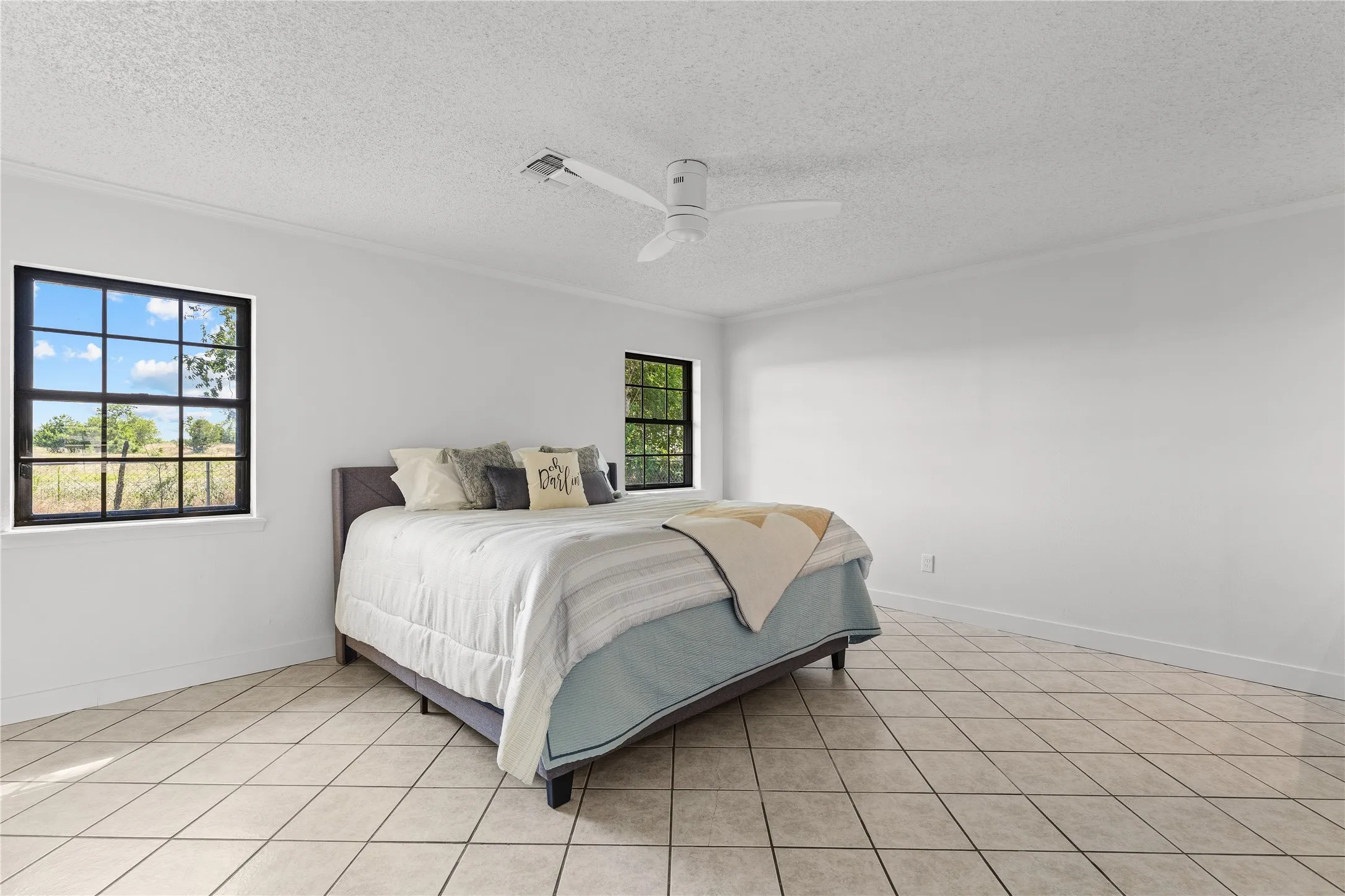 Spacious room featuring white walls, crown molding, and diagonal tile flooring