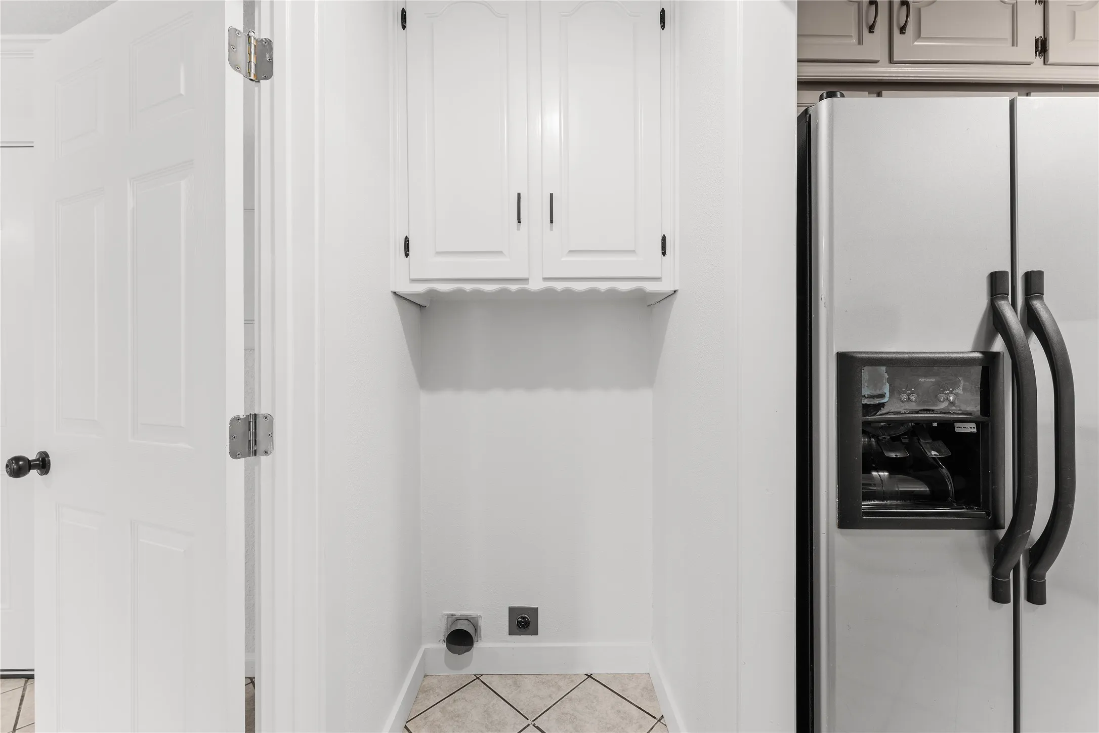 Dedicated laundry area featuring white cabinetry and tile flooring