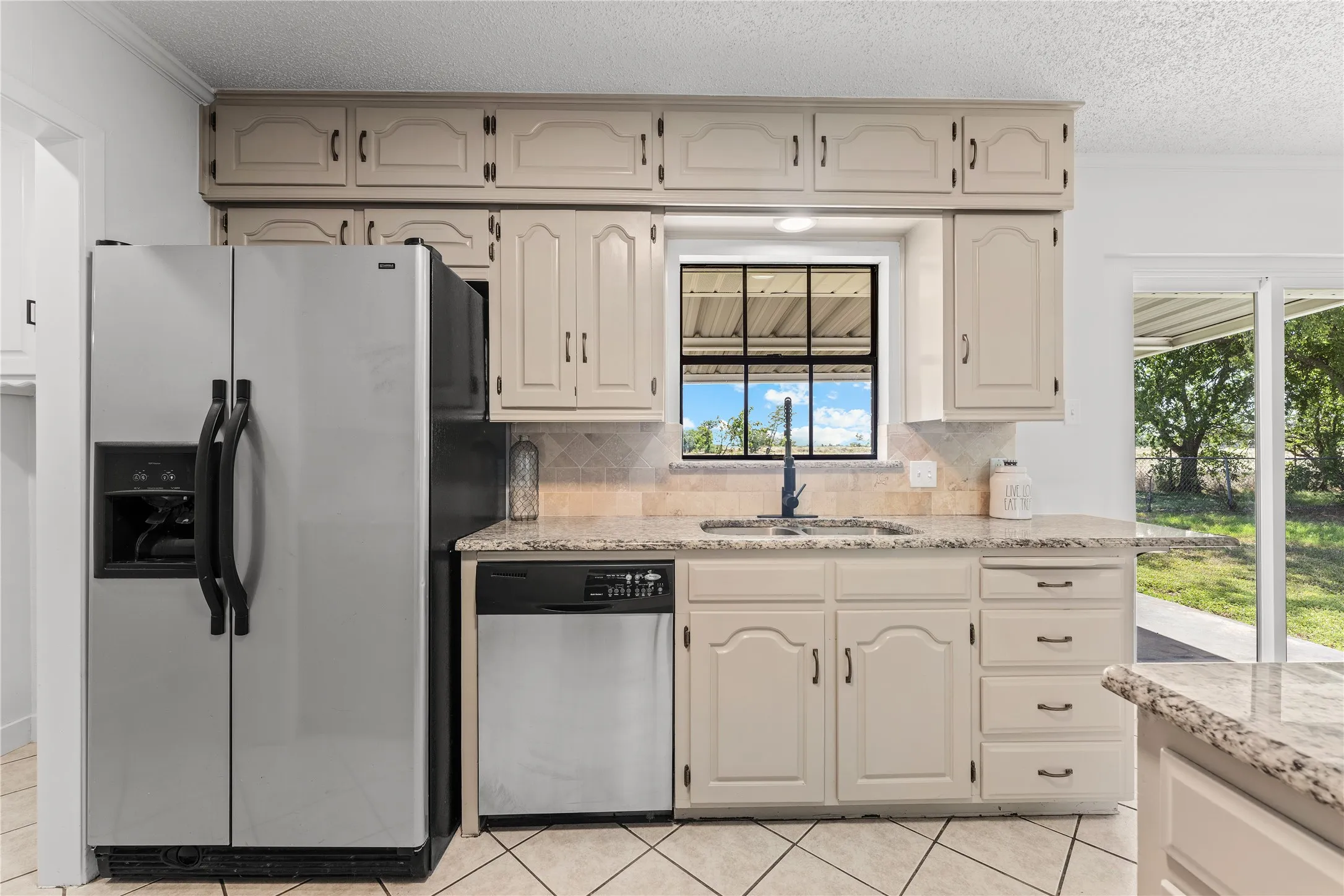 Kitchen featuring neutral cabinetry, a stainless steel side-by-side refrigerator, and a stainless steel dishwasher