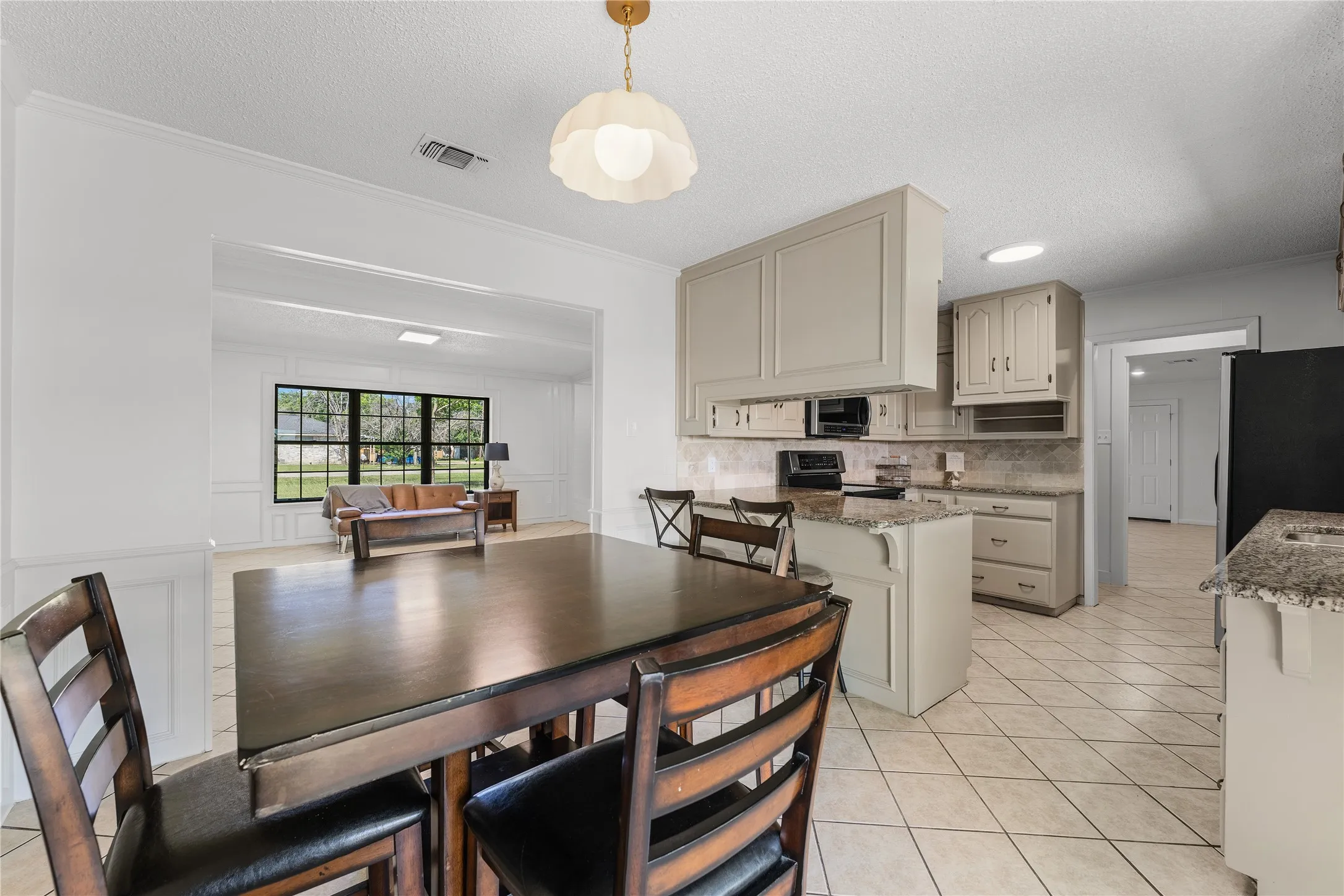 Kitchen area featuring light-toned cabinetry, granite countertops, and a tiled backsplash