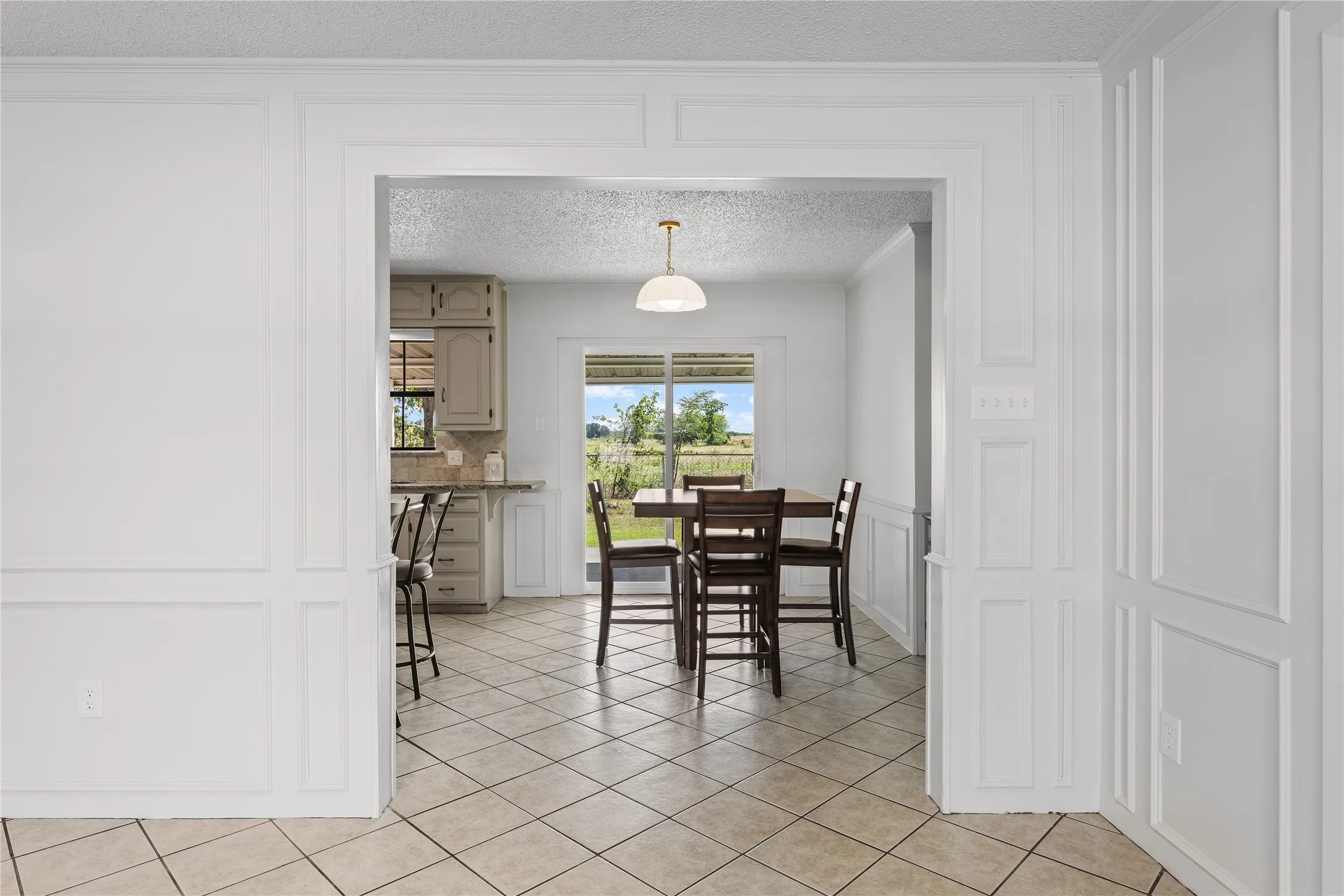 Archway entrance featuring custom wainscoting and tile flooring