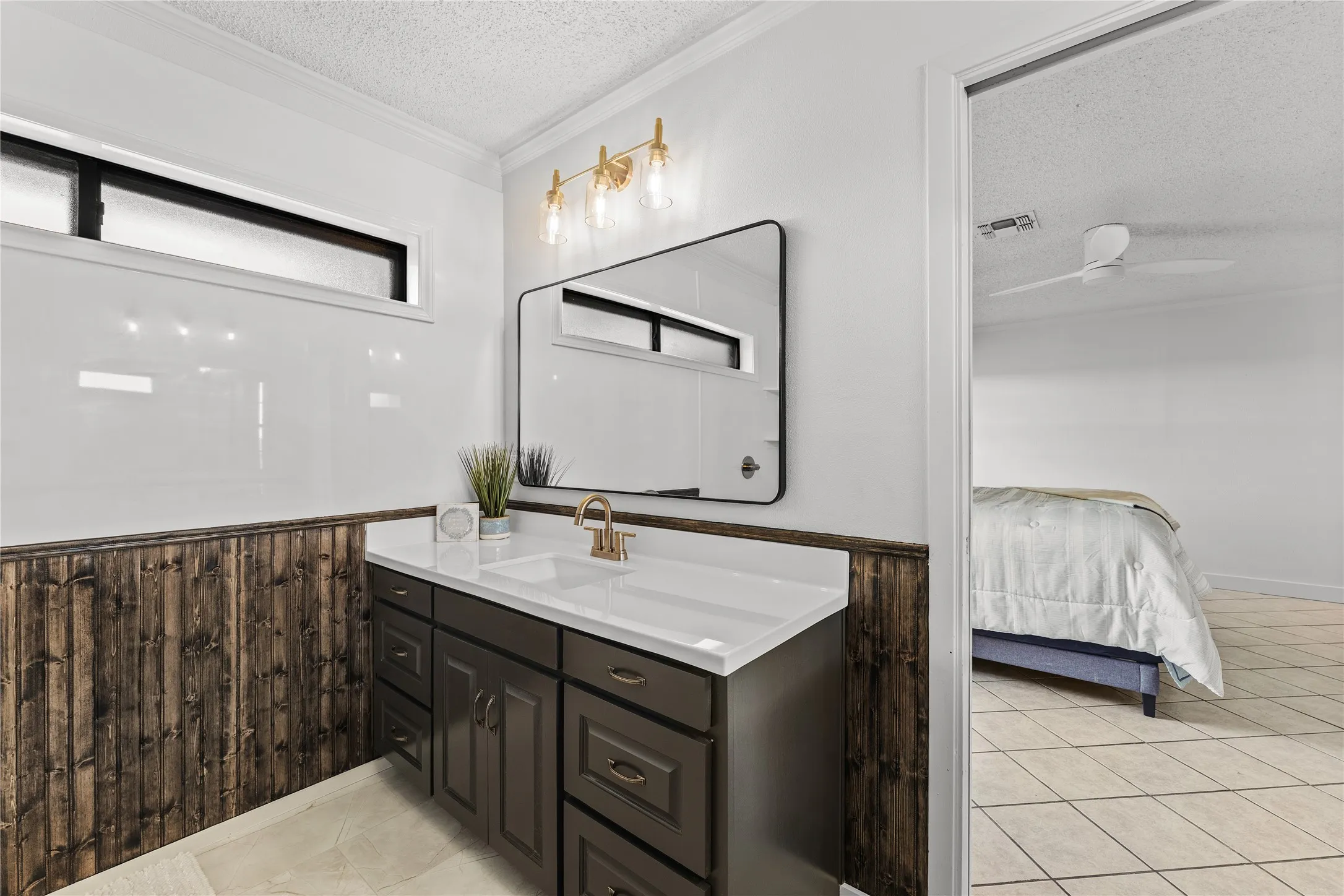 Bathroom vanity featuring a dark wood-finish cabinet, white countertop, and gold-tone faucet