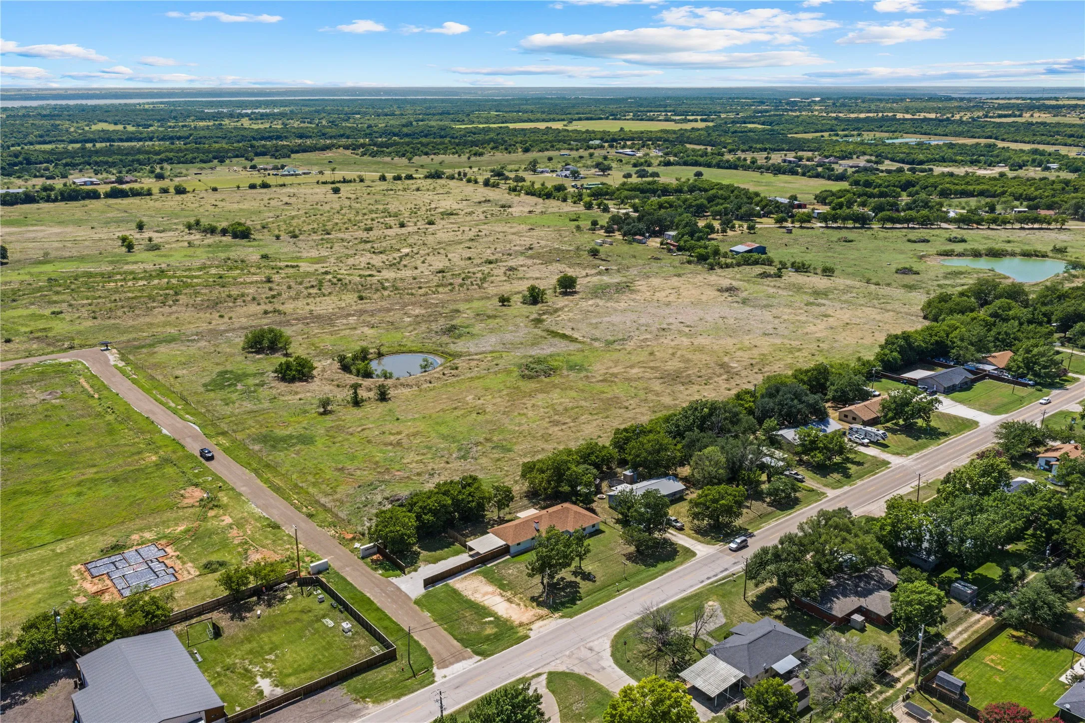 Expansive land parcel featuring open fields, a visible pond, and multiple mature trees