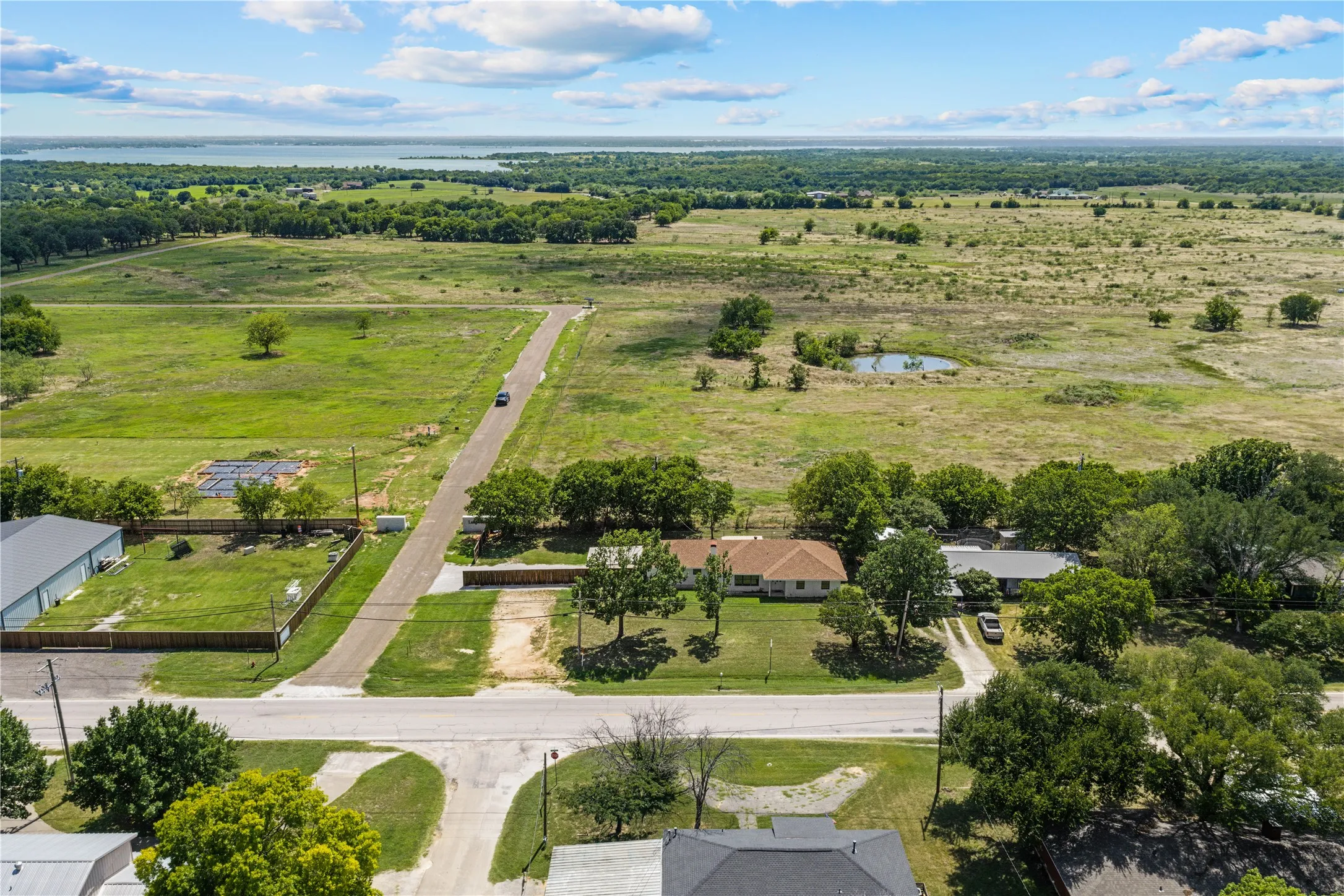 Expansive land parcel featuring open fields, a visible pond, and mature trees