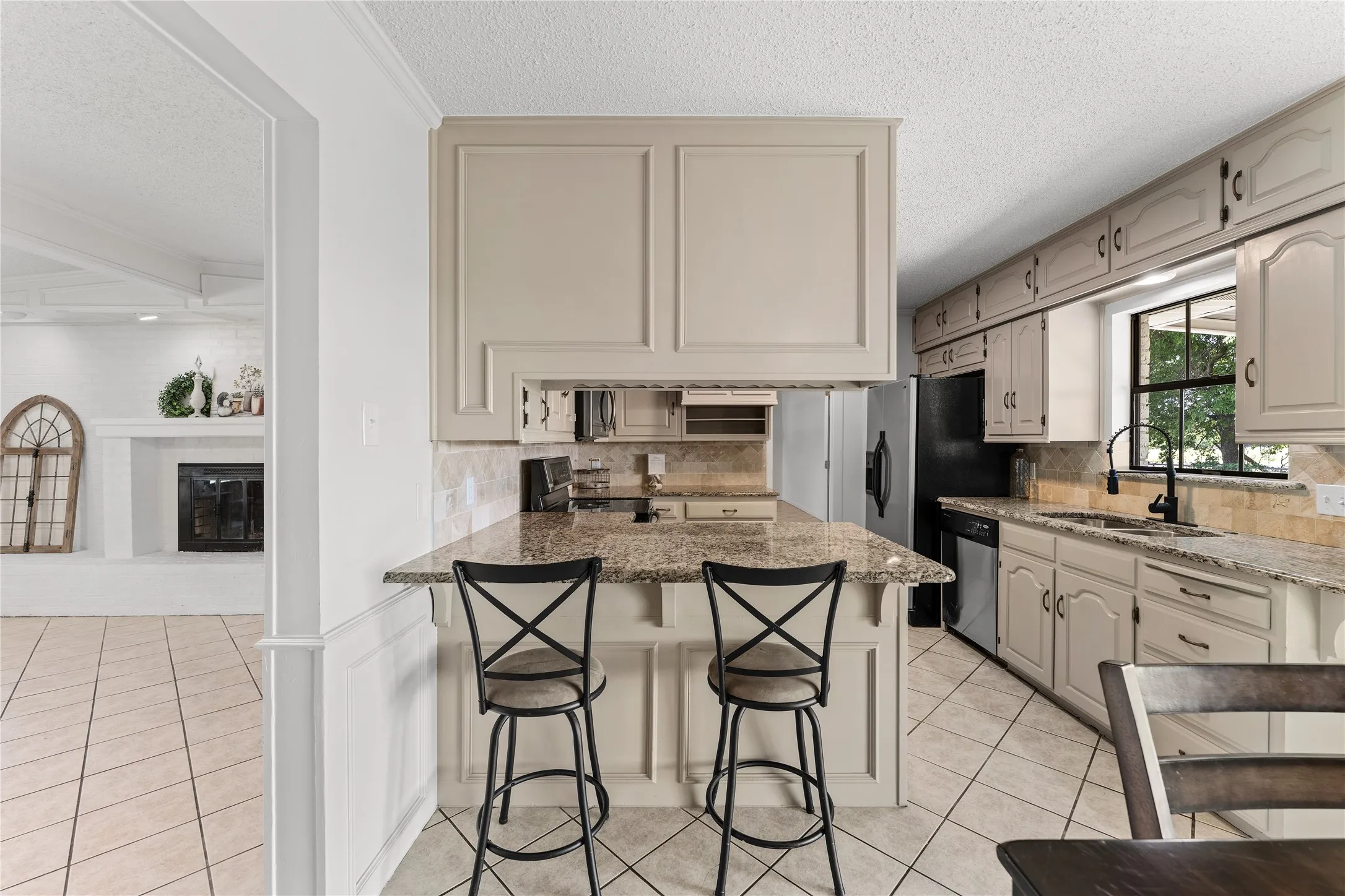 Kitchen featuring light-toned cabinetry, granite-finish countertops, and a tiled backsplash