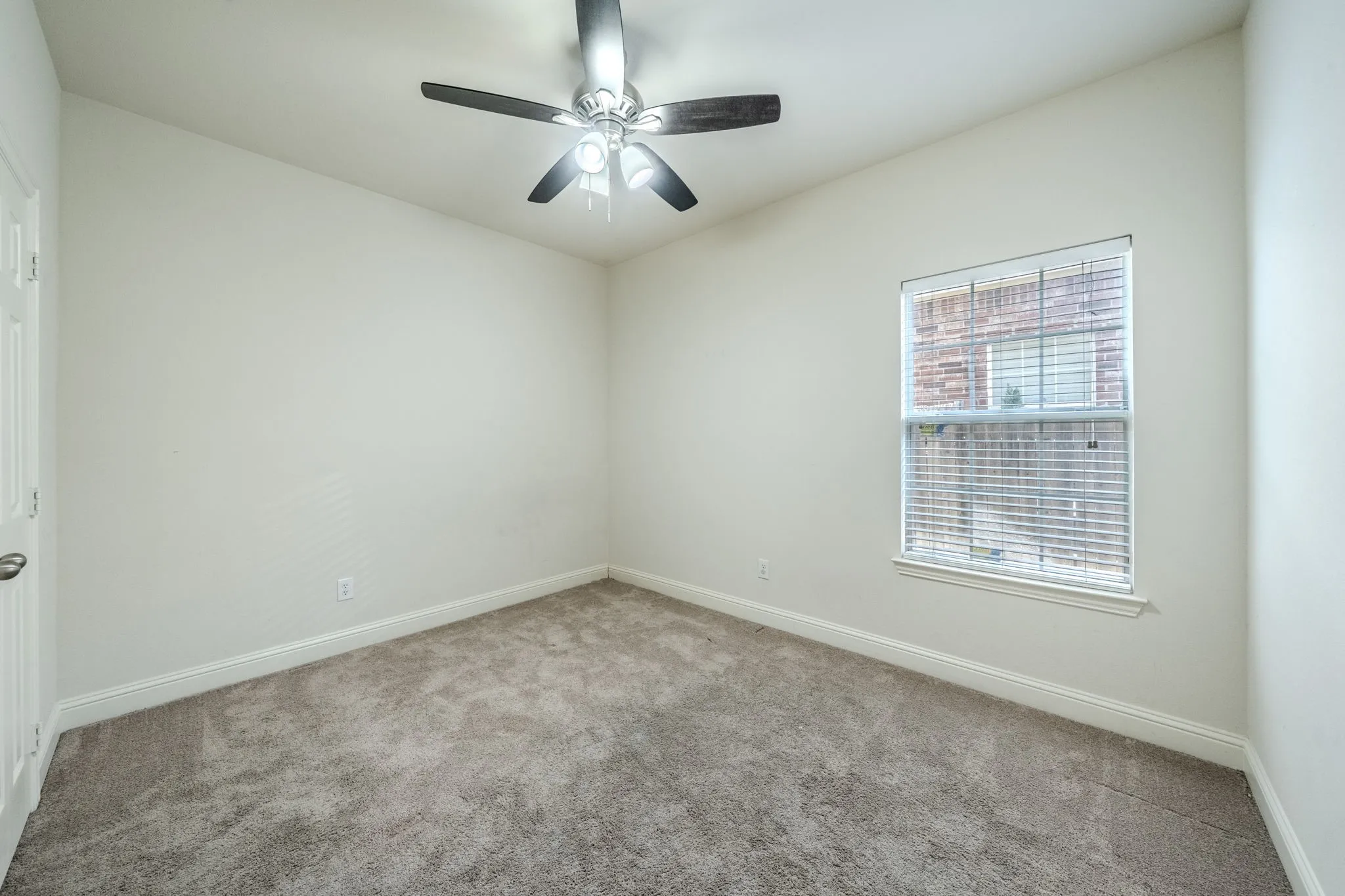 Neutral toned walls featuring a ceiling fan with integrated lighting, a window with horizontal blinds, and grey carpet flooring