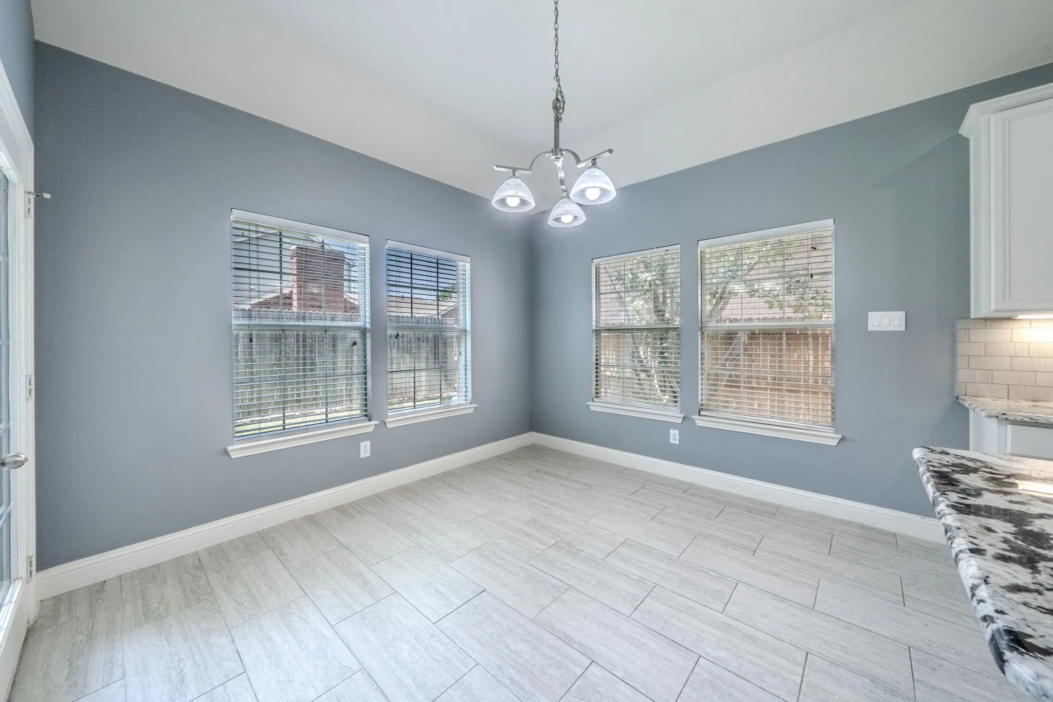 Dining area featuring light gray wall paint, an elegant chandelier, and multiple windows with blinds