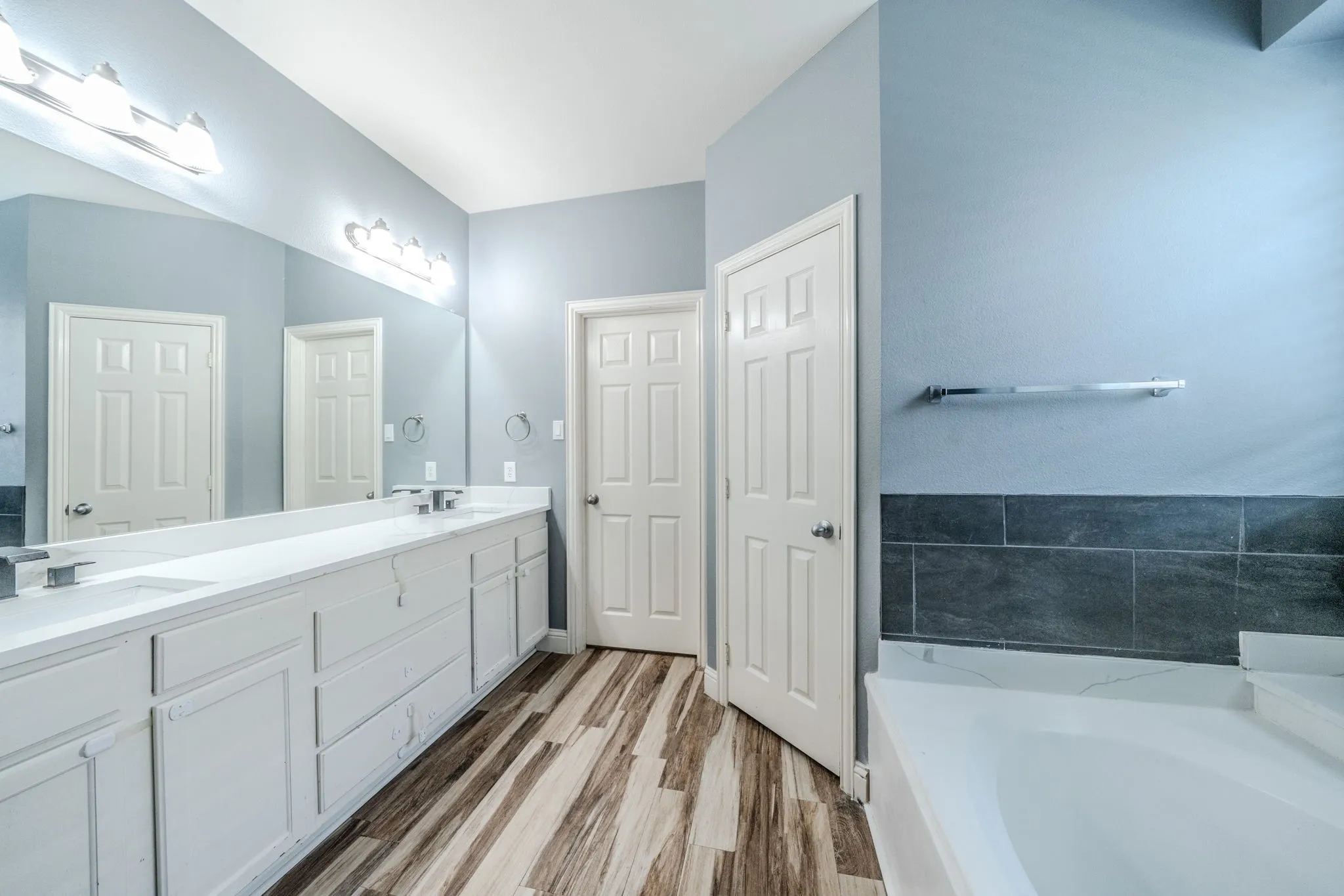 Bathroom featuring a long dual vanity with white cabinetry, integrated sinks, and chrome faucets