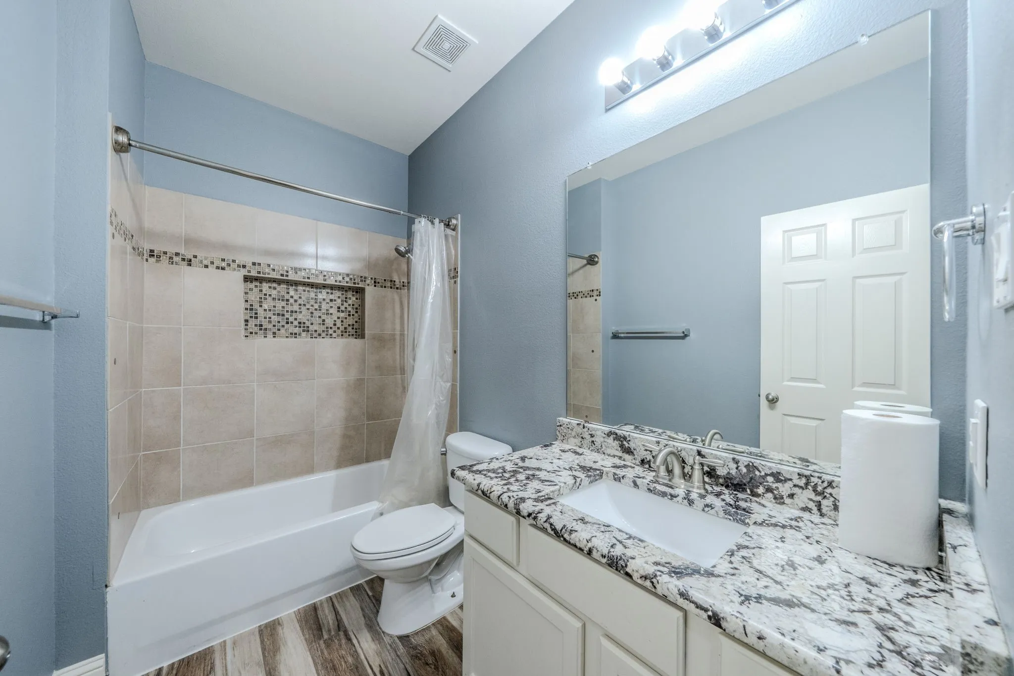 Bathroom featuring a white tub with tiled surround, mosaic tile accent, and recessed niche