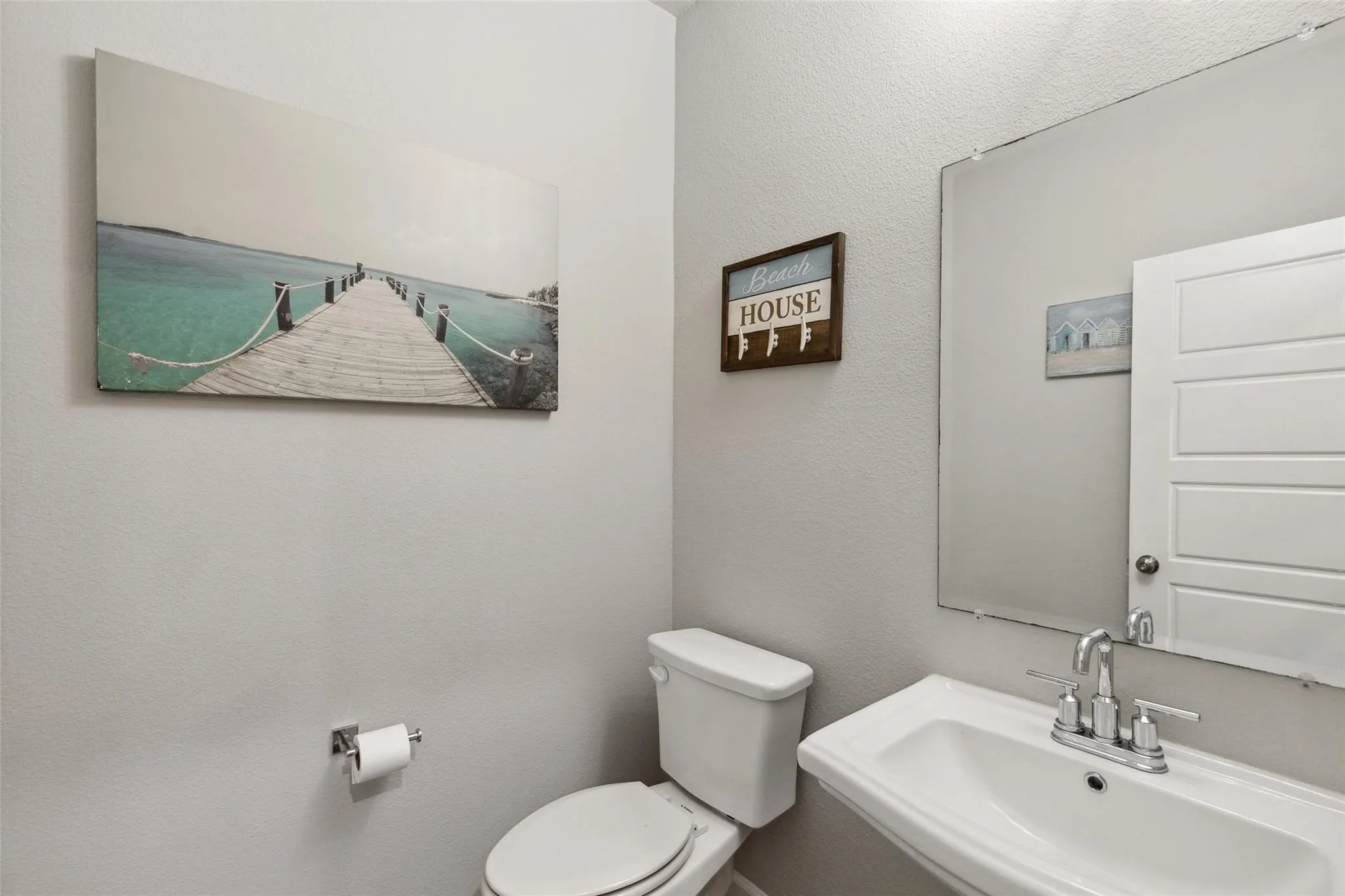 1st Floor Half Bath - Powder room with a pedestal sink, chrome faucet, wall-mounted mirror, and a two-piece toilet