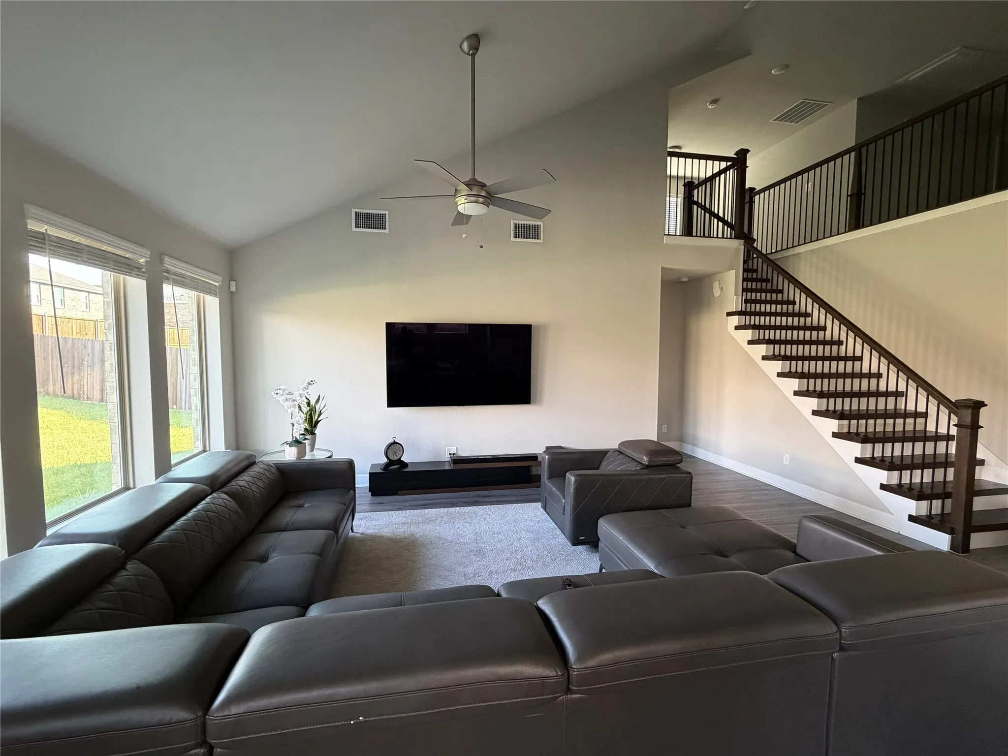 Spacious living area featuring a vaulted ceiling and a ceiling fan
