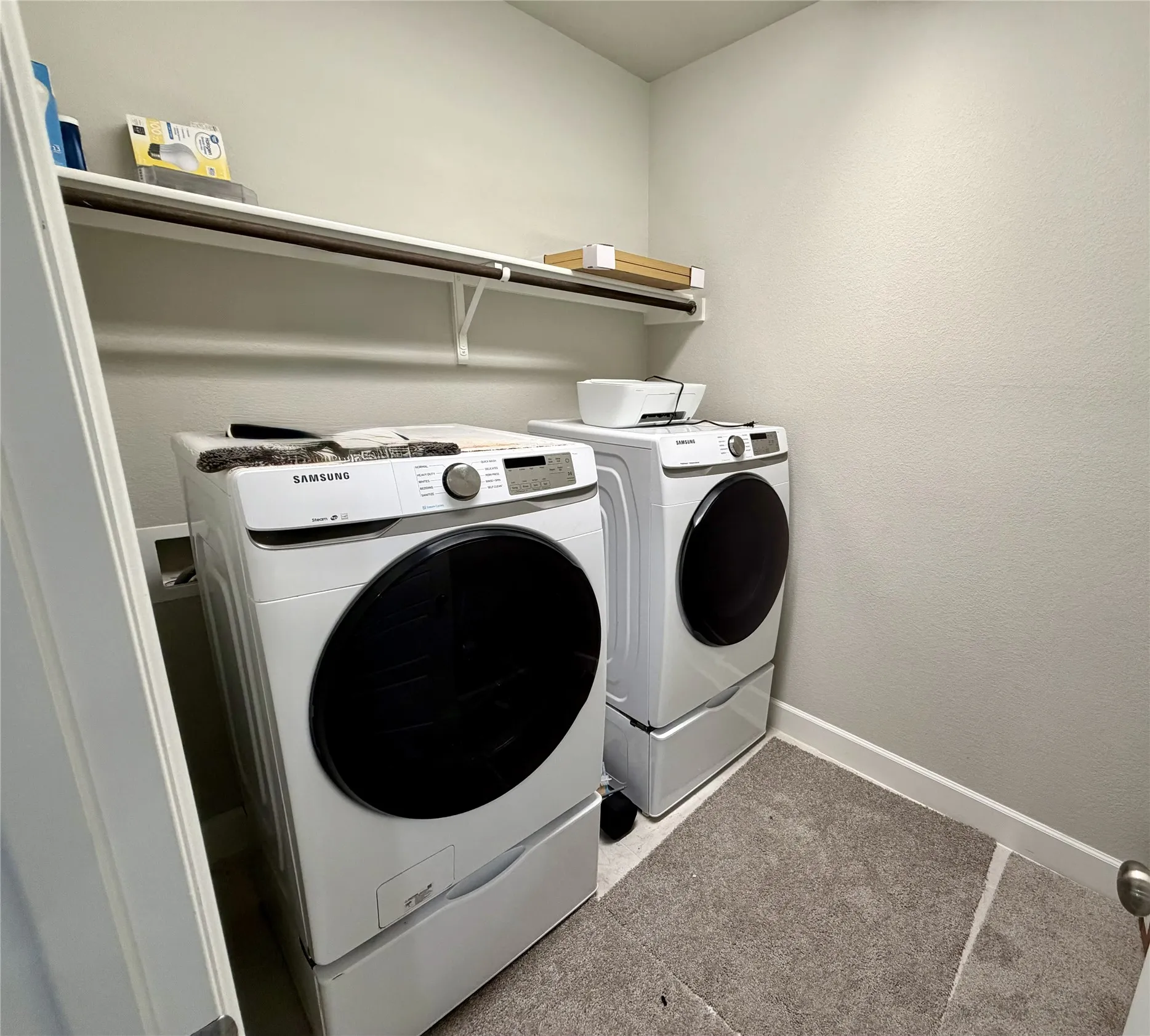 Dedicated laundry area featuring a wall-mounted storage shelf