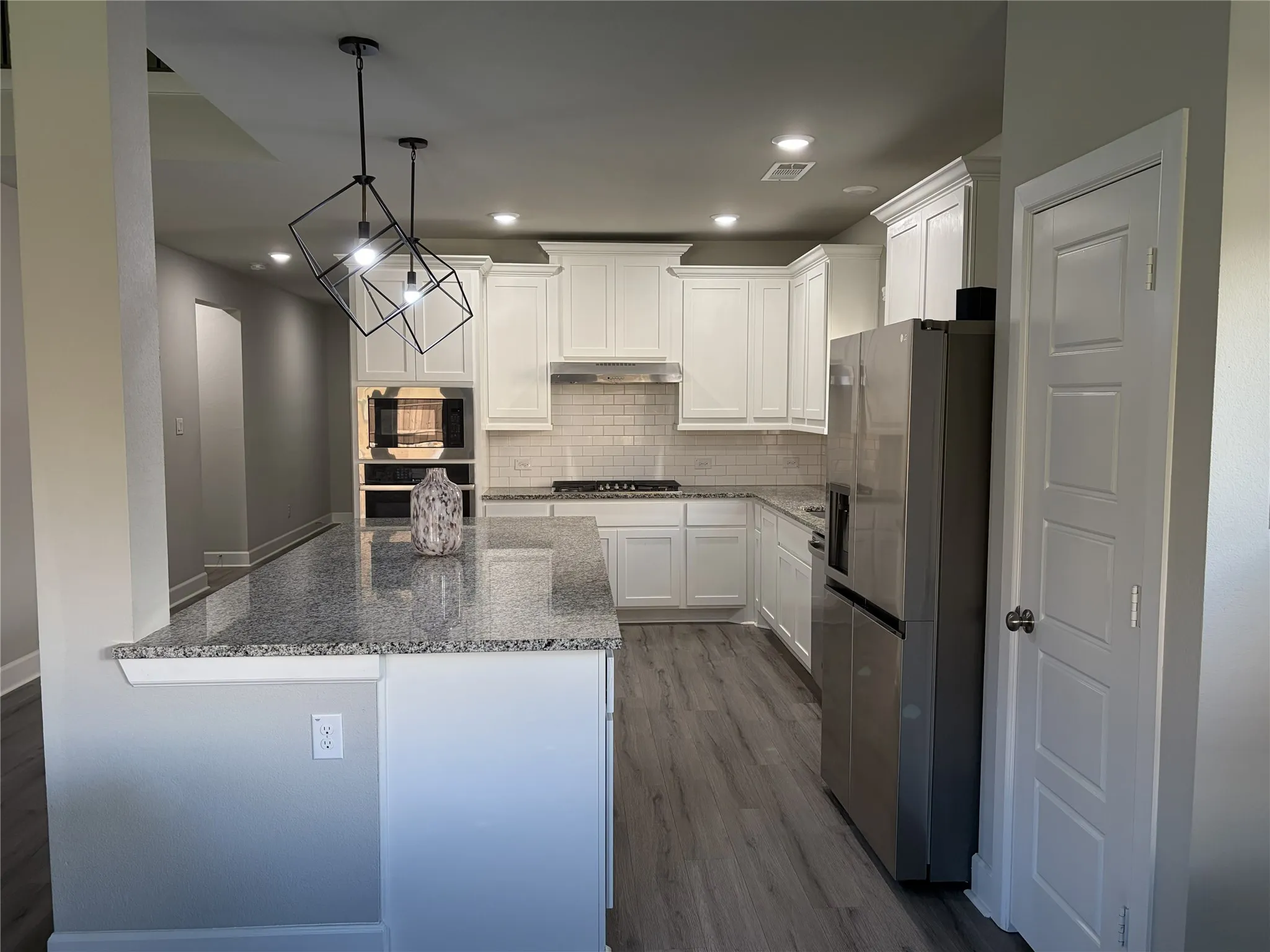 Modern kitchen featuring a granite-topped island with pendant lighting