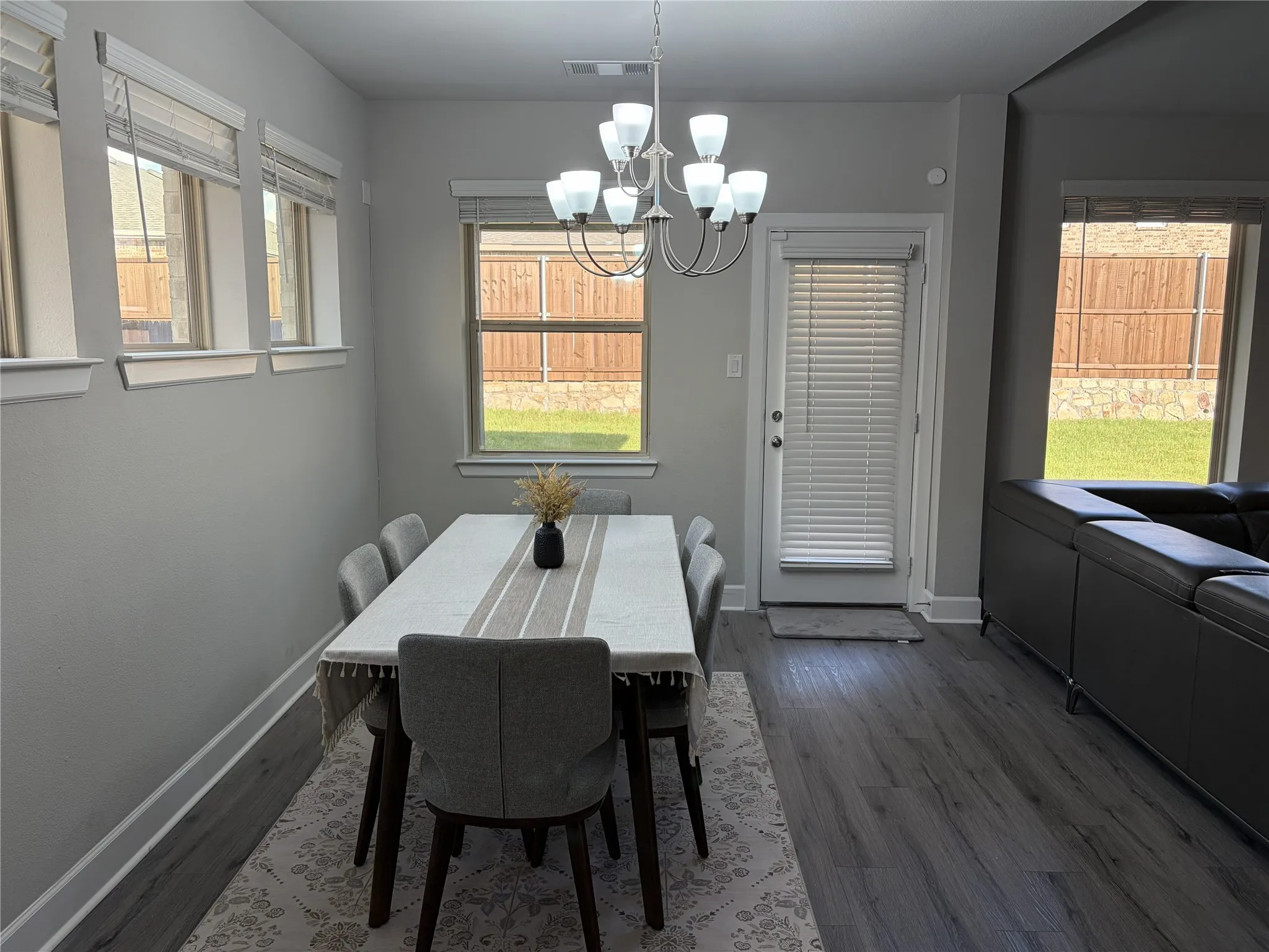 Dining area featuring wood-finish flooring, a contemporary chandelier, and multiple windows providing natural illumination