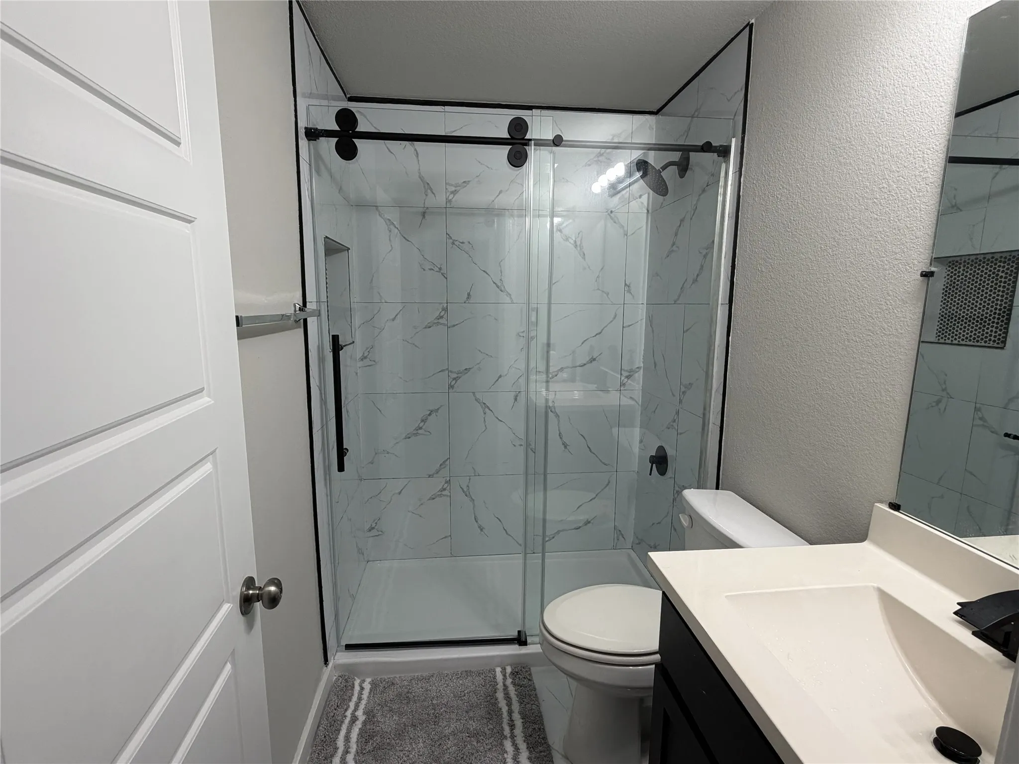 2nd Floor Bath 2 Contemporary bathroom featuring a walk-in shower with clear glass barn doors and black hardware