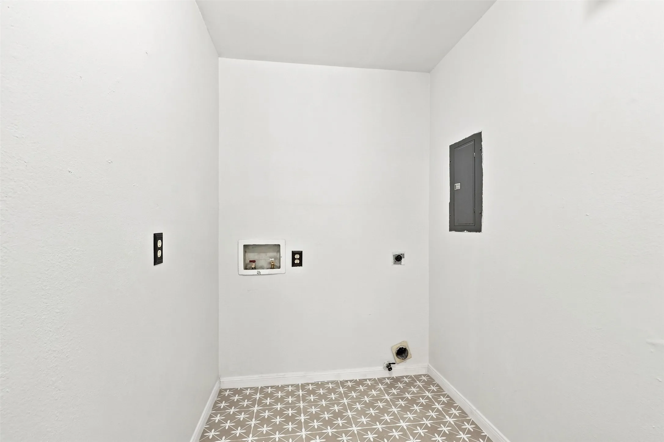 White walls with a textured finish, patterned floor tiles, and a visible electrical panel