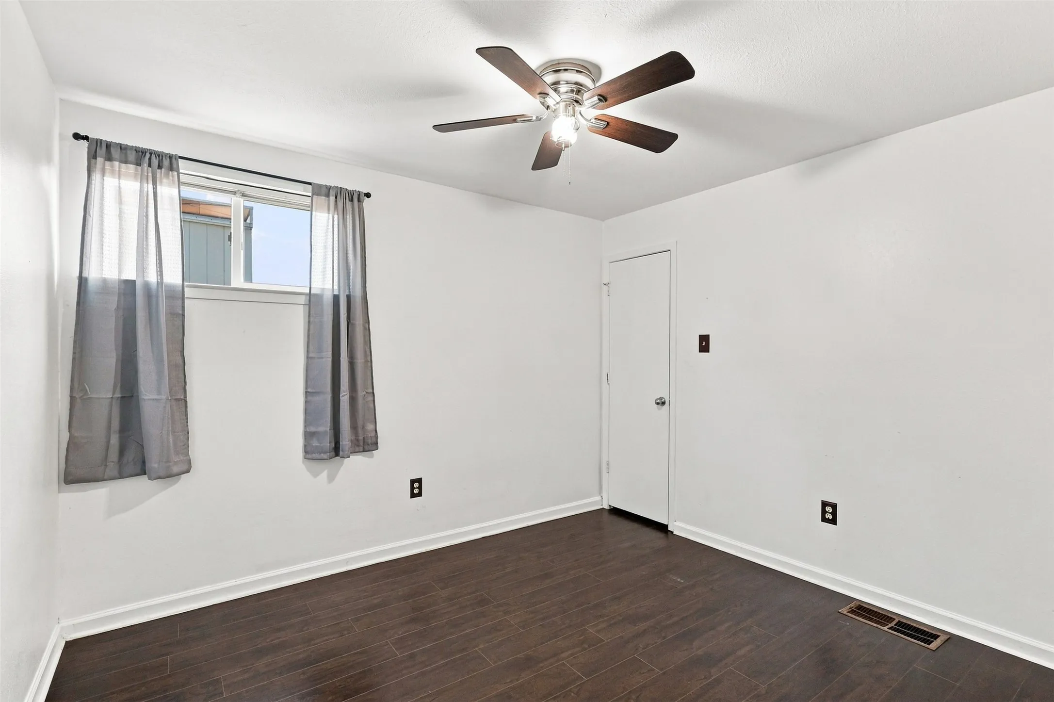 Recessed window with white trim, wood-finish flooring, white walls, and a ceiling fan with light fixture
