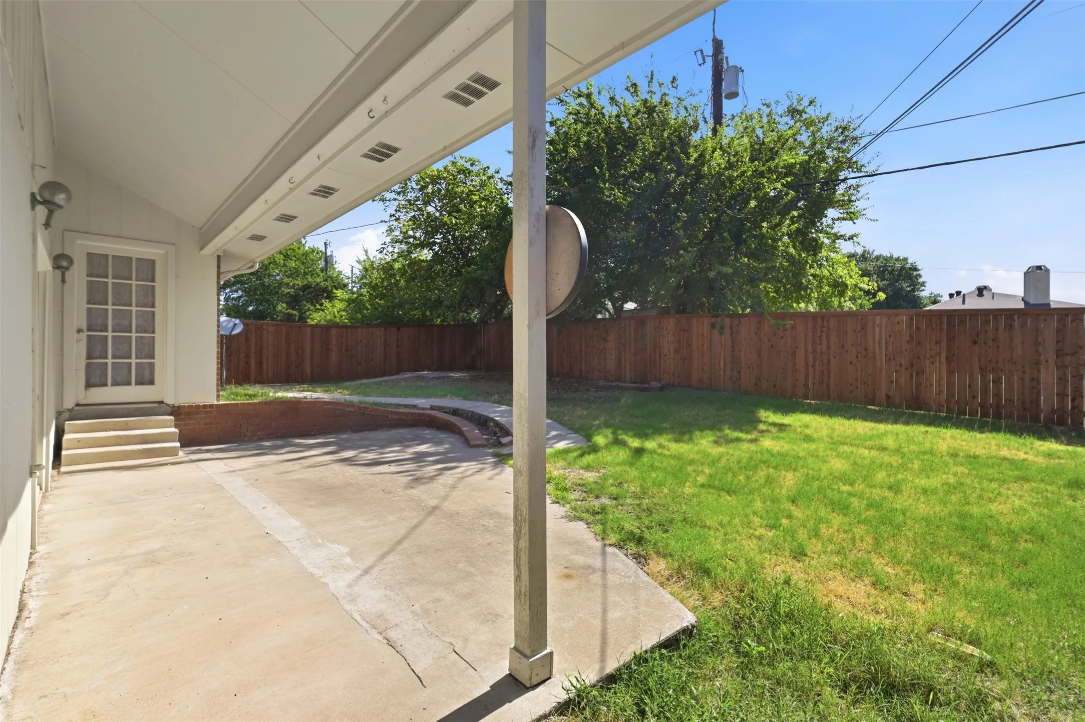 Covered concrete patio with recessed lighting and a privacy fence