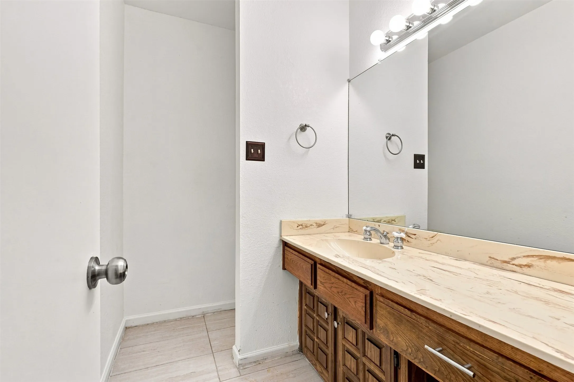 Integrated vanity with an undermount sink, a polished chrome faucet, and a large wall-mounted mirror with an overhead light fixture
