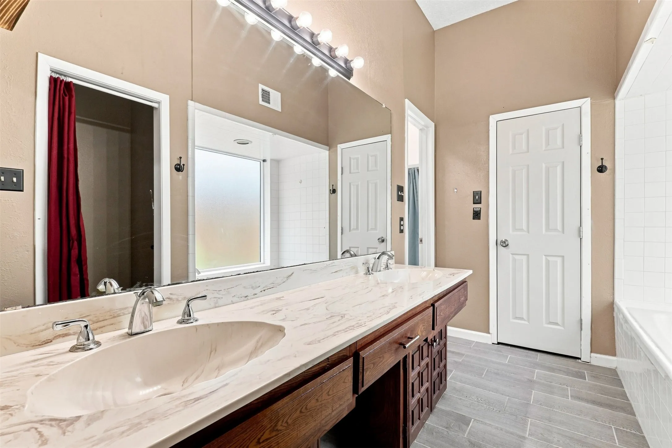 Dual vanity with integrated sinks, a large mirror, a separate shower enclosure, and a bathtub