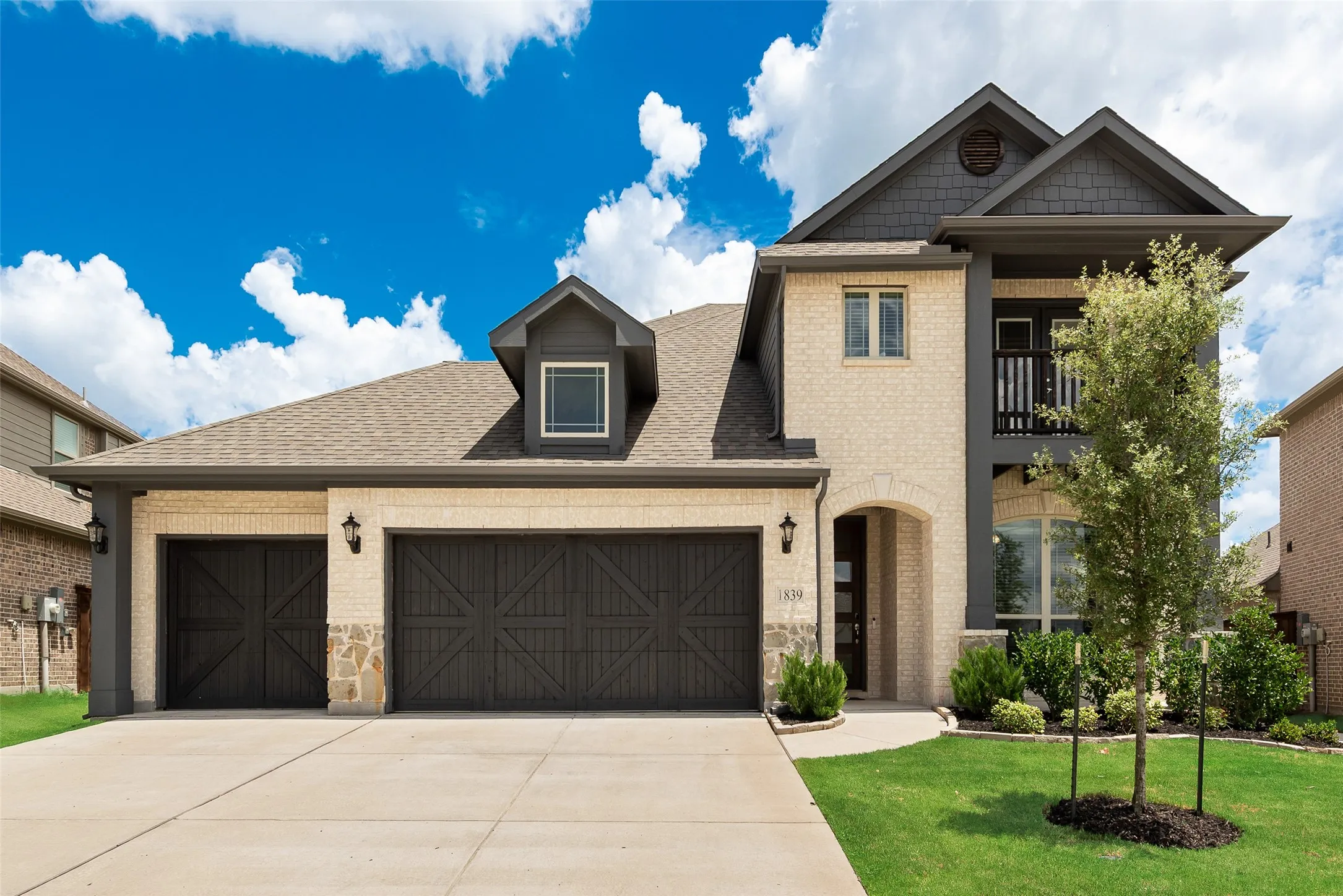Contemporary residence featuring a light brick facade and dark wood-finish garage doors