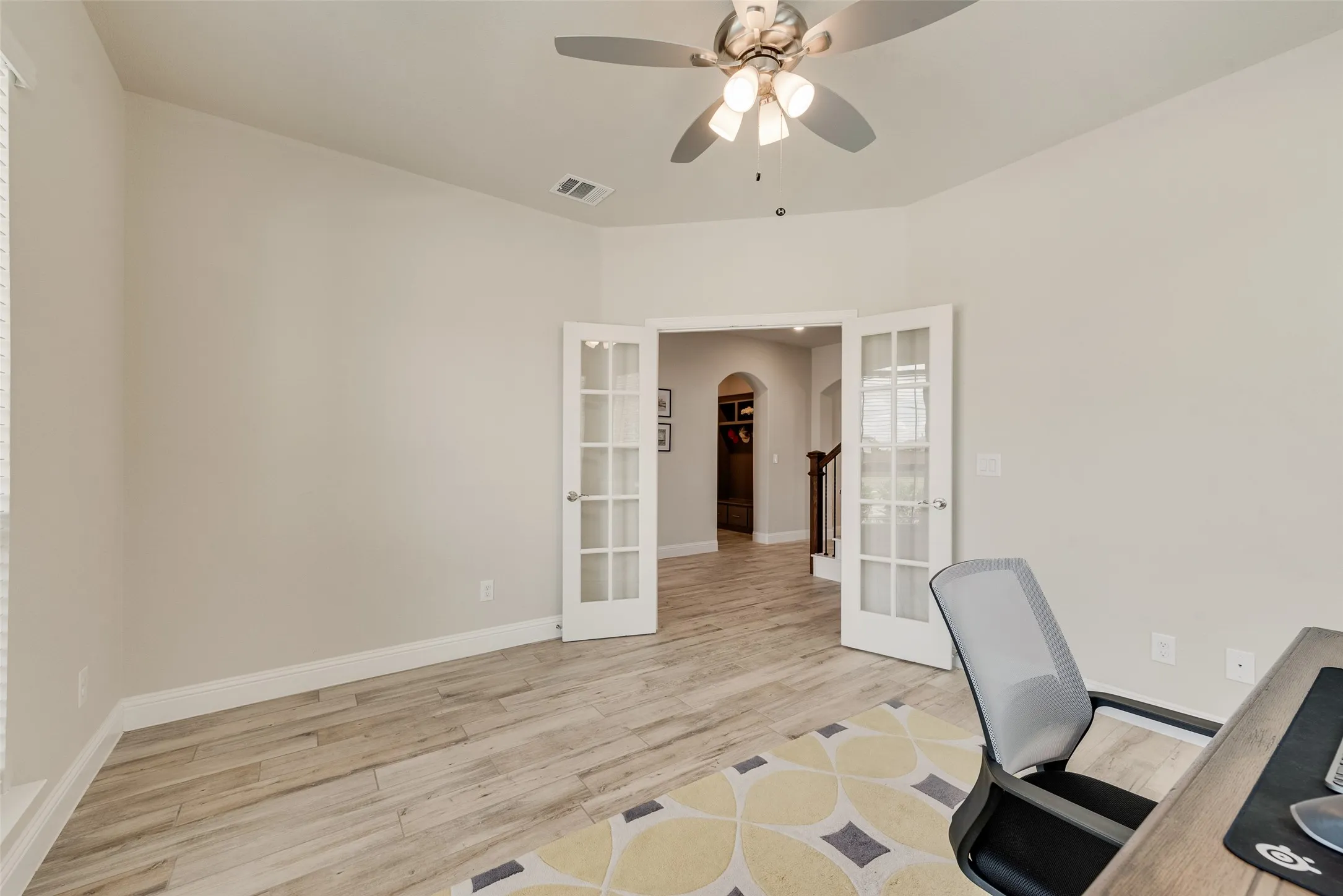 Room featuring wood-finish flooring, light neutral walls, and a ceiling fan with integrated lighting