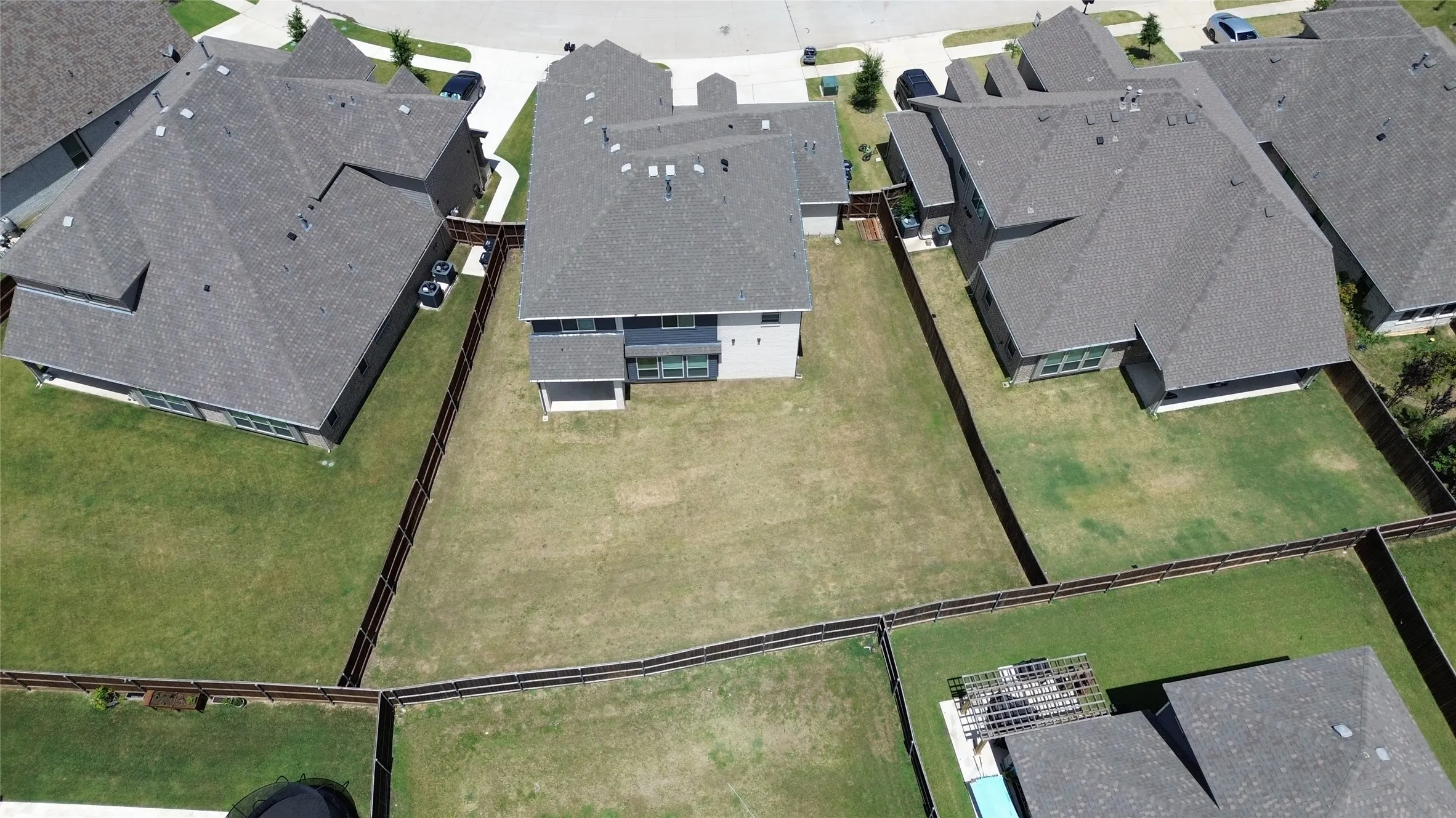 Expansive backyard featuring a manicured lawn, full perimeter fencing, and a concrete patio