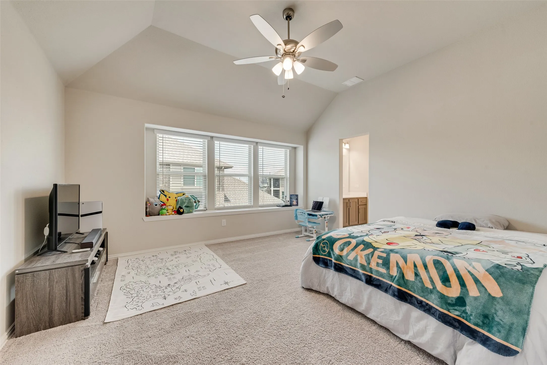 Spacious bedroom featuring vaulted ceilings, a ceiling fan with integrated lighting, and a large window with horizontal blinds and an integrated window seat