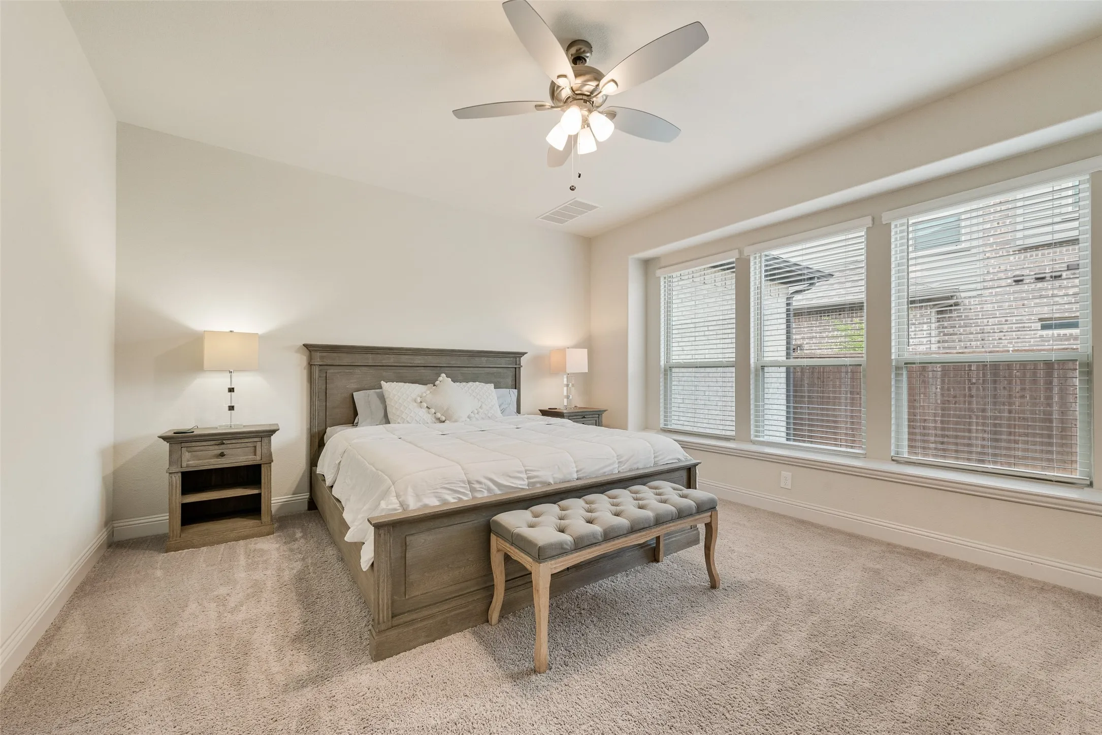 Carpeted room featuring a ceiling fan with integrated lighting, three large windows with blinds, and white baseboards