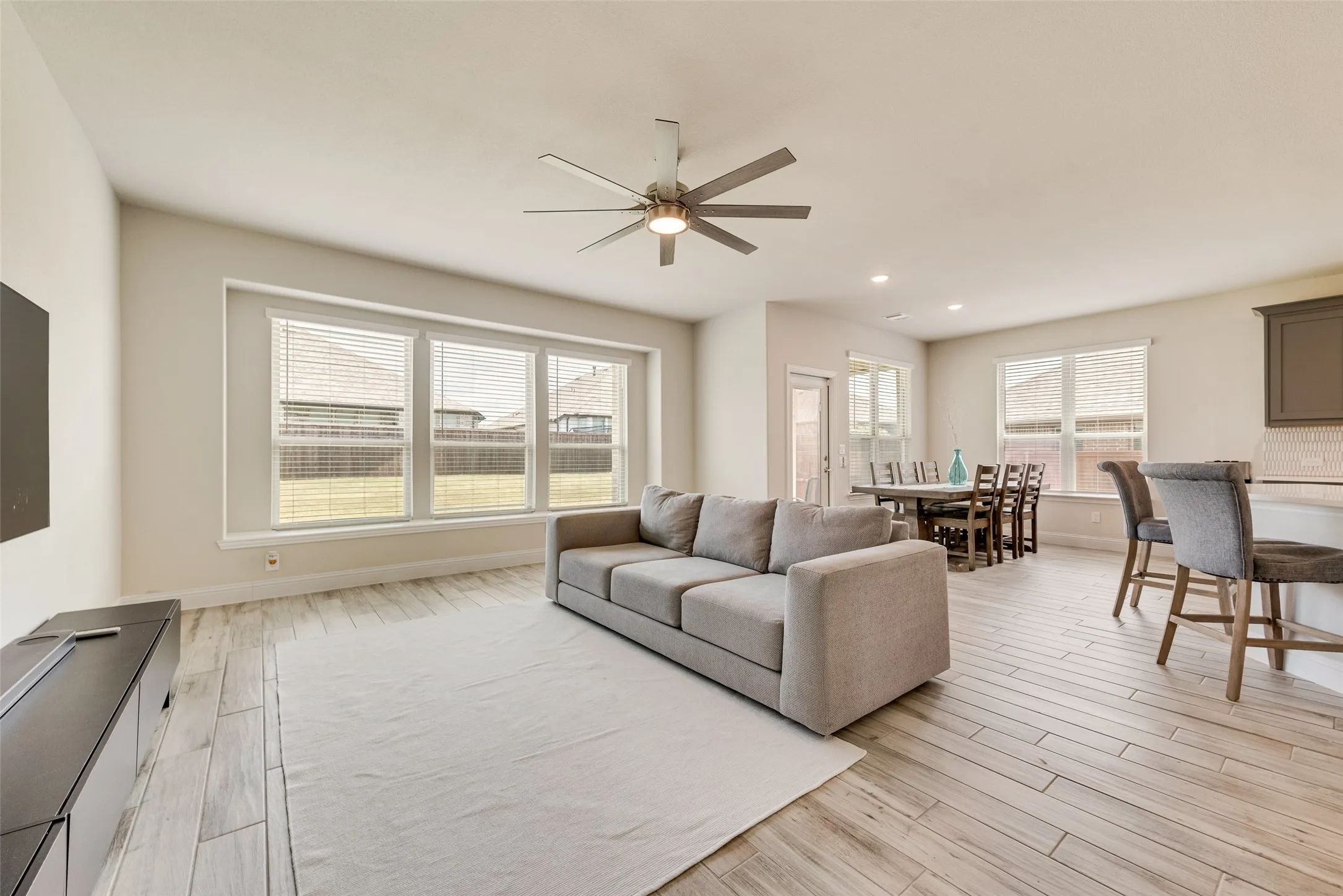 Open-concept living area featuring wood-finish flooring, a contemporary ceiling fan, and recessed lighting