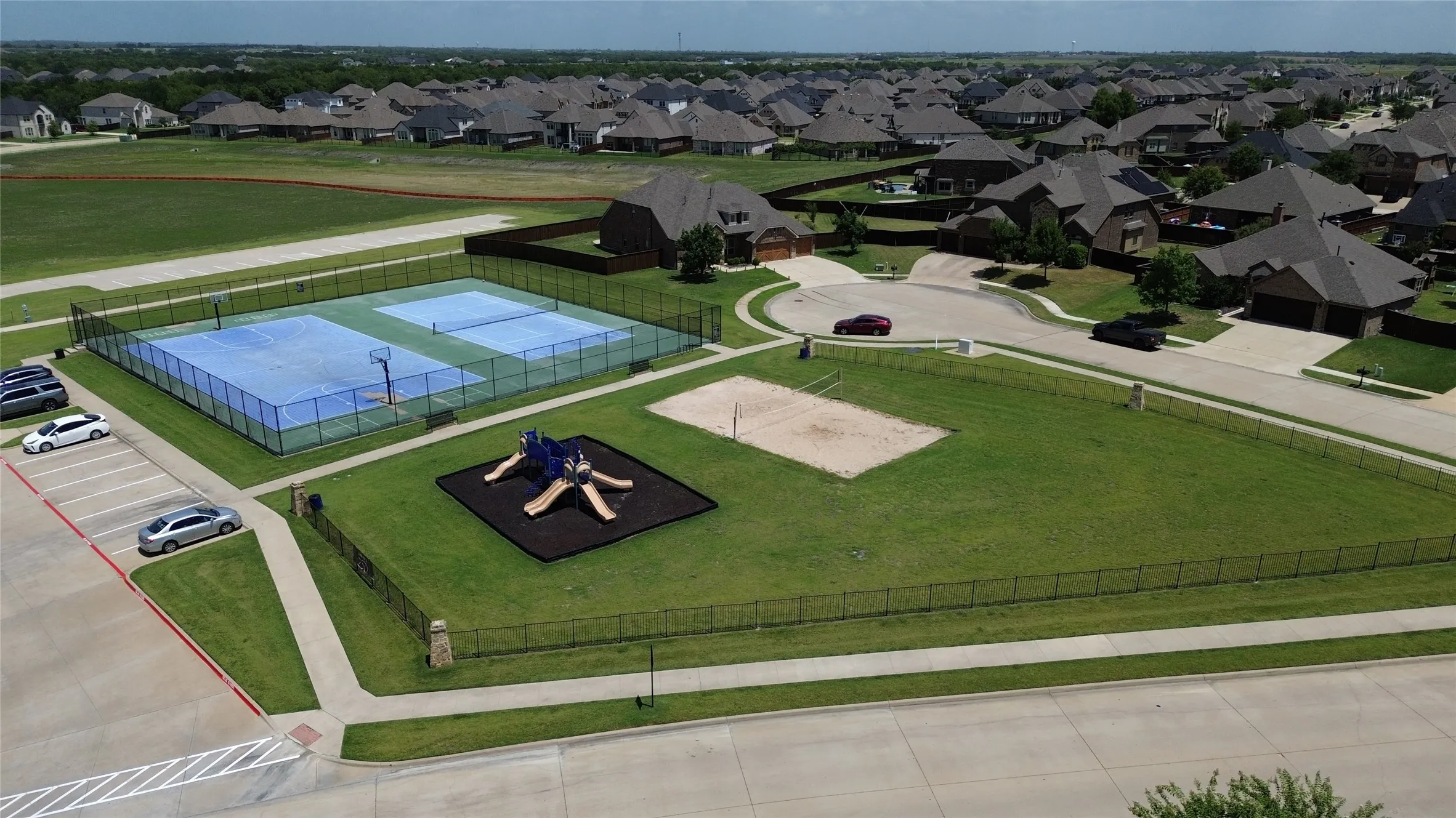 Community amenities featuring two fenced sports courts, a playground with soft surfacing, and a sand court