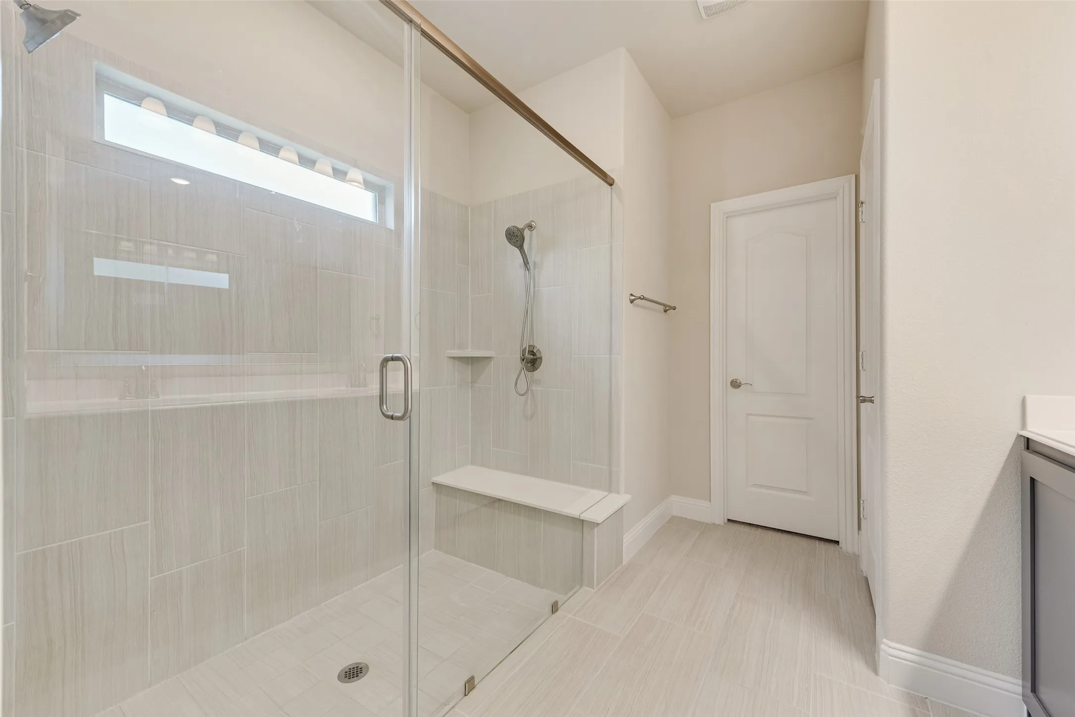 Walk-in shower with clear glass enclosure and bronze-finish hardware